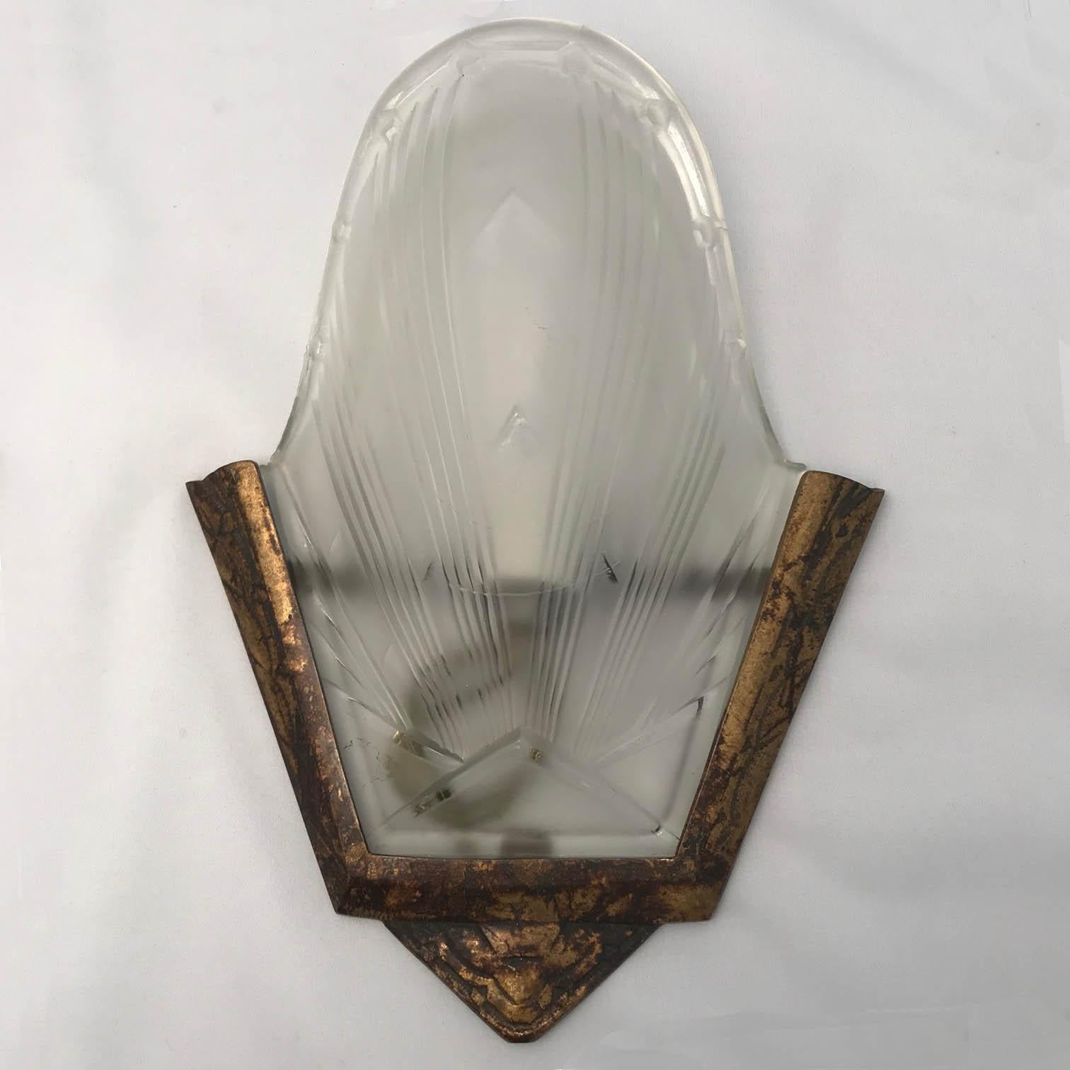 This pair is evocative of the two great masters. The textured bronze in the manner of Edgar Brandt, the bulbous shade in the manner of Lalique. As the photo shows, the ribbed and frosted glass radiates from a triangular centre. The shade slides