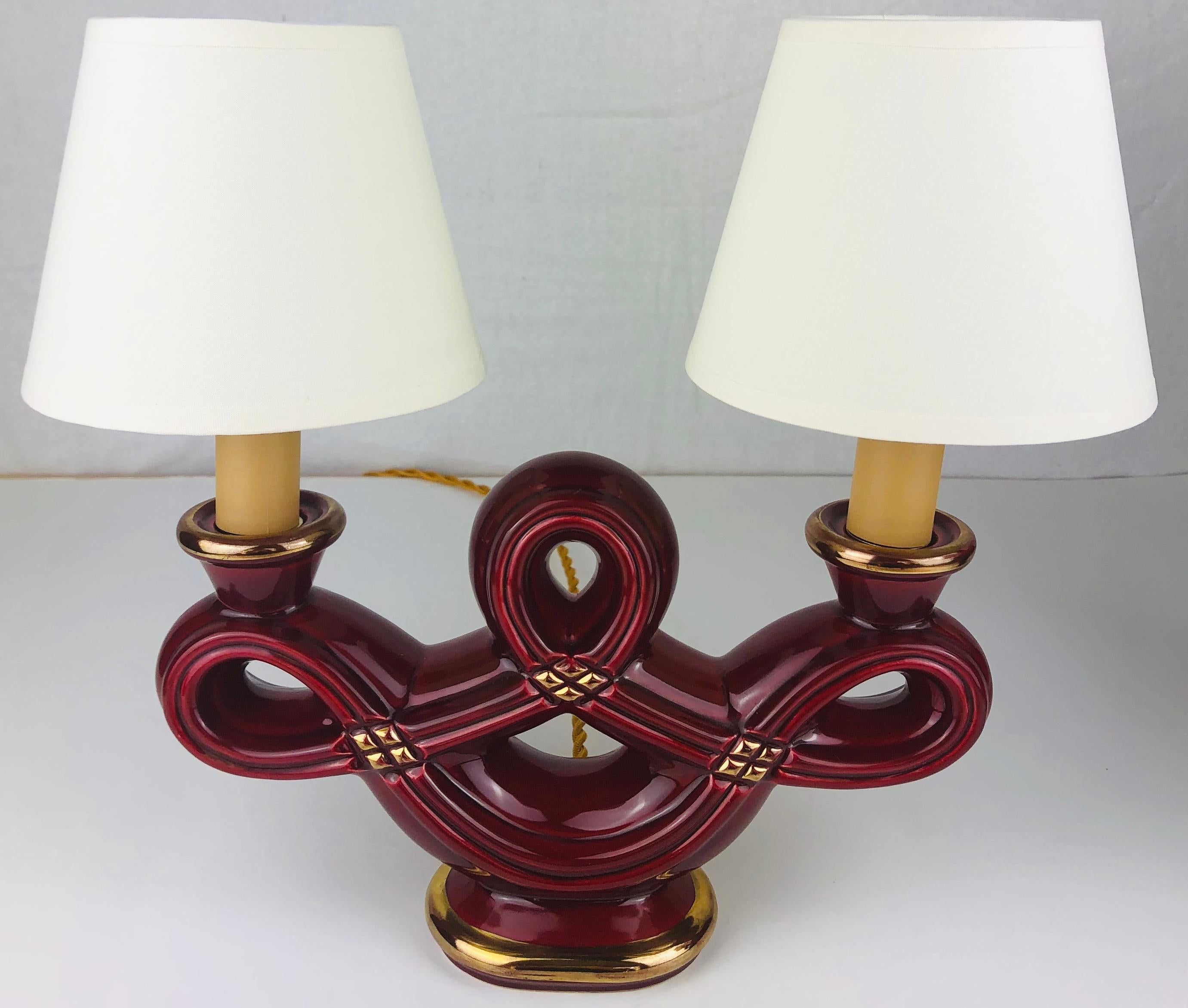 Very decorative pair of French Art Deco swirled faience candle stands converted to table lamps. These beautiful lamps are very good quality and in perfect condition.

The striking burgundy color with gold trim and diamond shaped details are very