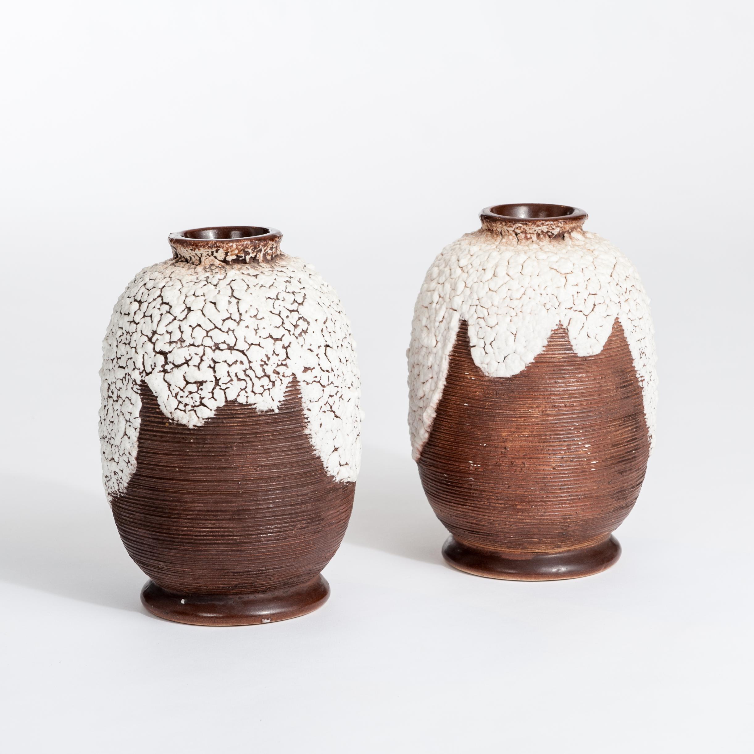 Coppia di vasi in ceramica Art Deco francese marrone-bianco firmati da Louis Auguste Dage.
La superficie di colore marrone scuro ha una struttura a coste sottili, mentre la parte superiore presenta una decorazione in ceramica 