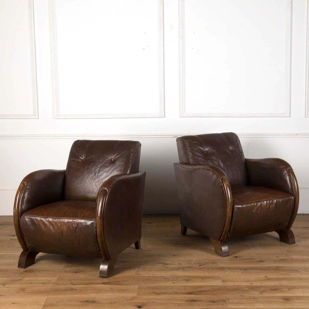 A pair of French Art Deco style club chairs, upholstered in their original leather with walnut detail, circa 1930.