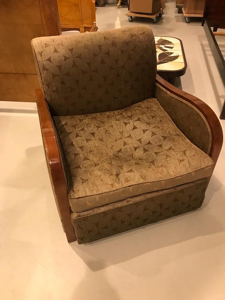 This pair of French Art Deco club chairs is from the 1930s. The large and comfortable chairs have an exposed beechwood arm that continues to form the front feet. The wood continues along the side of the chair where it meets the same wood on the