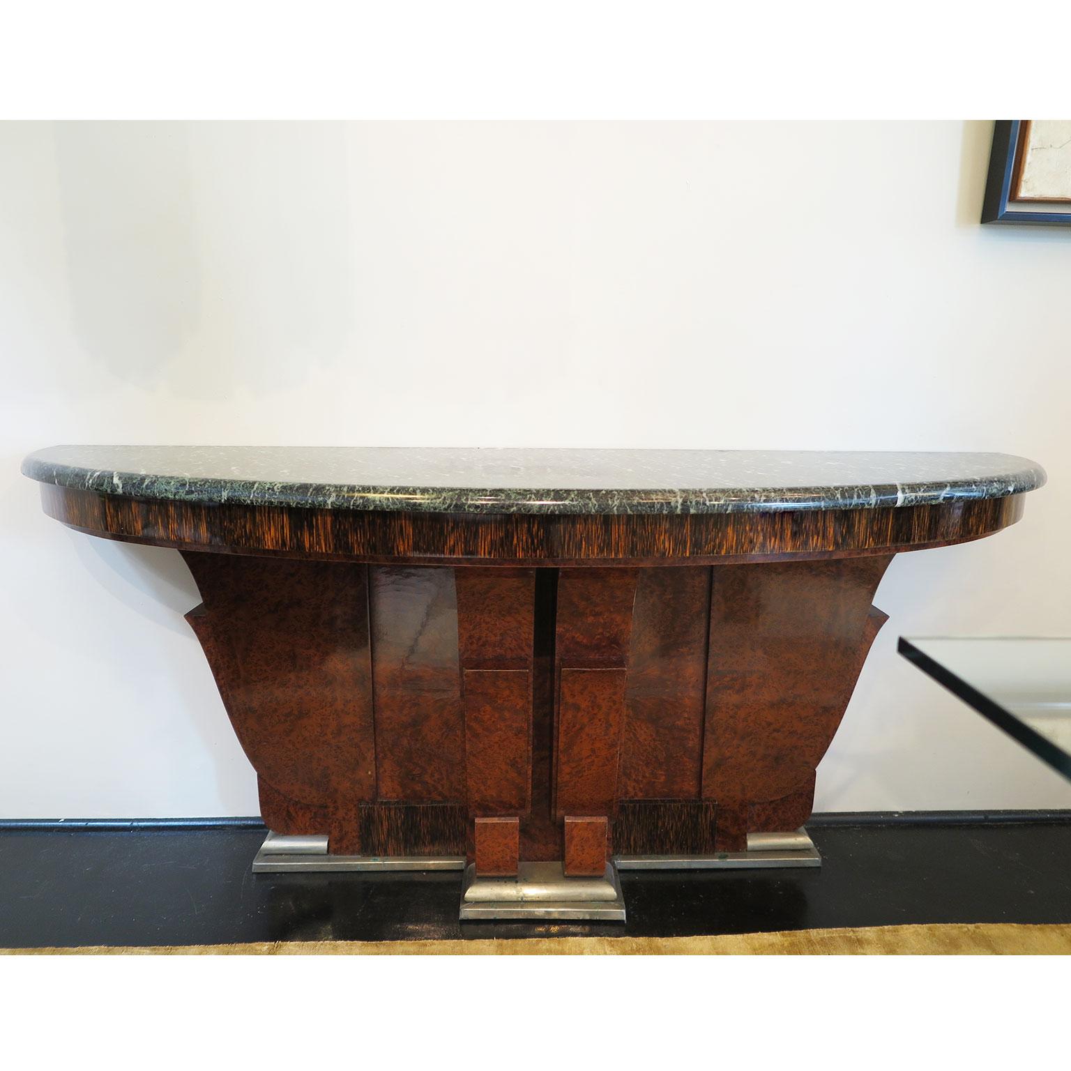 These beautiful consoles are fully in original condition. Crafted in a Mapa burl wood veneer the base showcases curved carving designs with a base foot in aged nickel. The apron displays a unique palmwood veneer with the top possessing the original