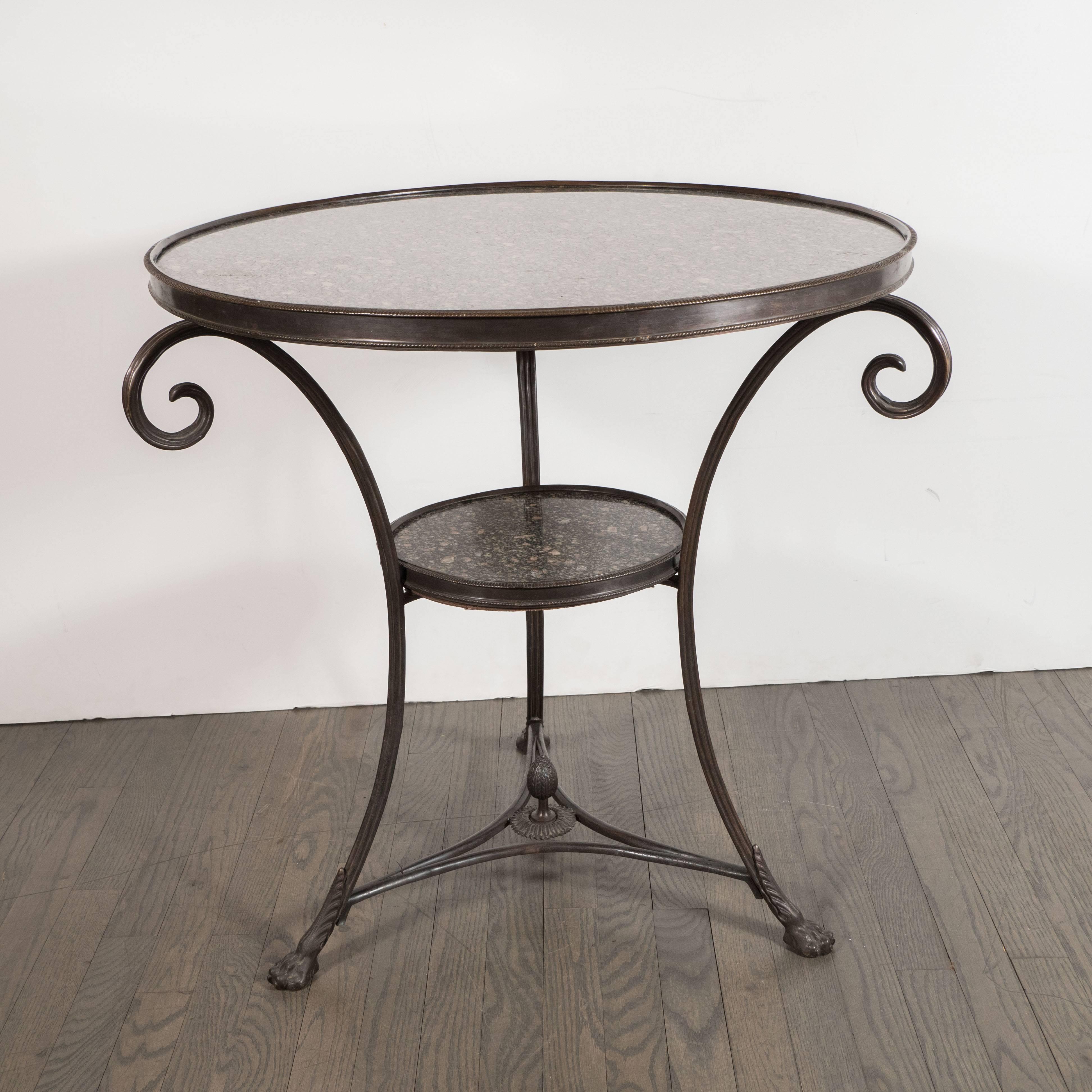 This dramatic and refined pair of Art Deco gueridon tables were realized in France, circa 1930. They feature two tiers of round granite tops circumscribed by bronze which is inscribed throughout with vertical striations. They are supported by