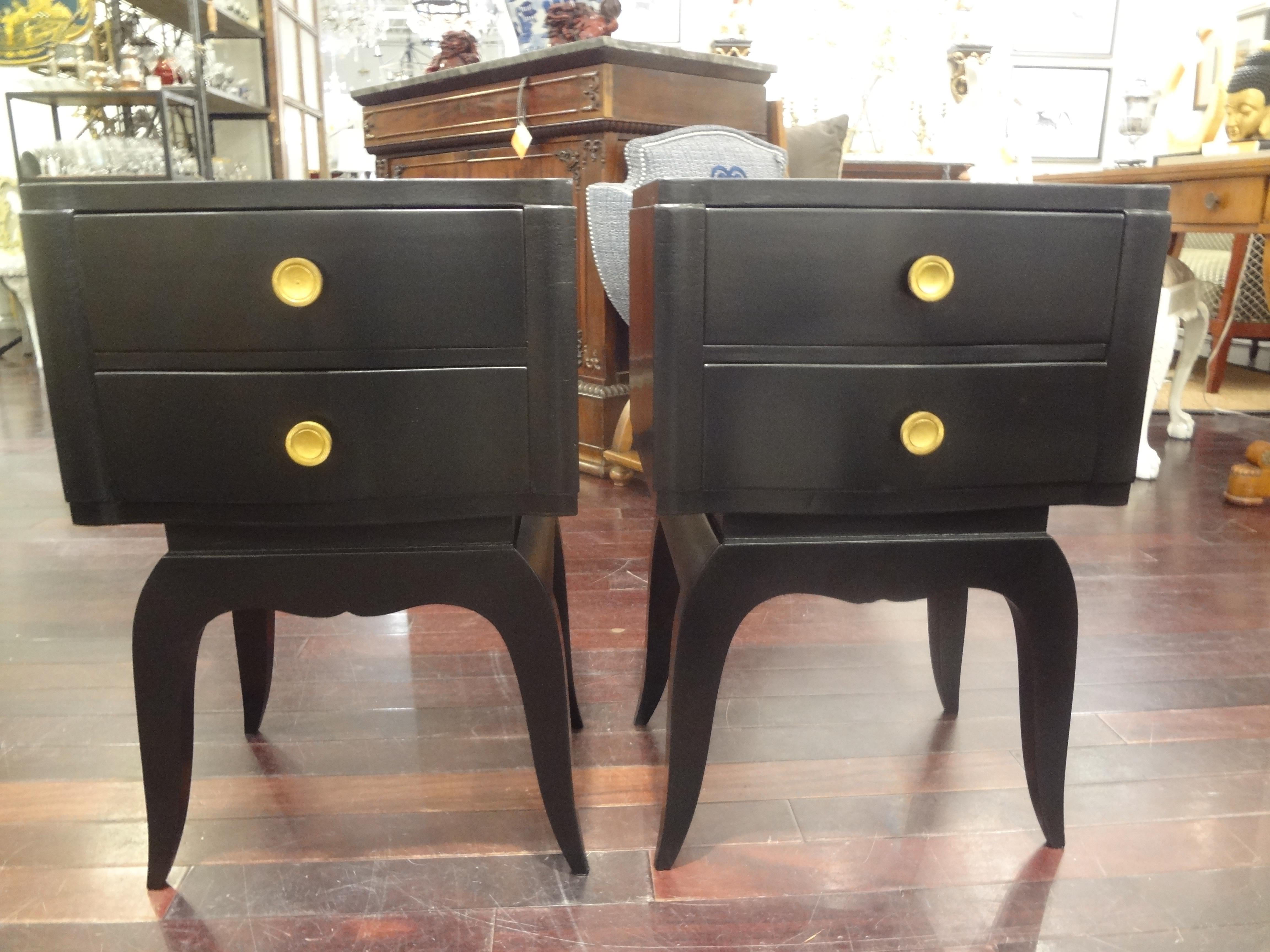 Stunning pair of French Art Deco ebonized commodes, chests, nightstands or side tables with two drawers and bronze hardware. This versatile pair of Jules Leleu inspired tables would work well in a variety of interiors and rooms and date to the 1930s.