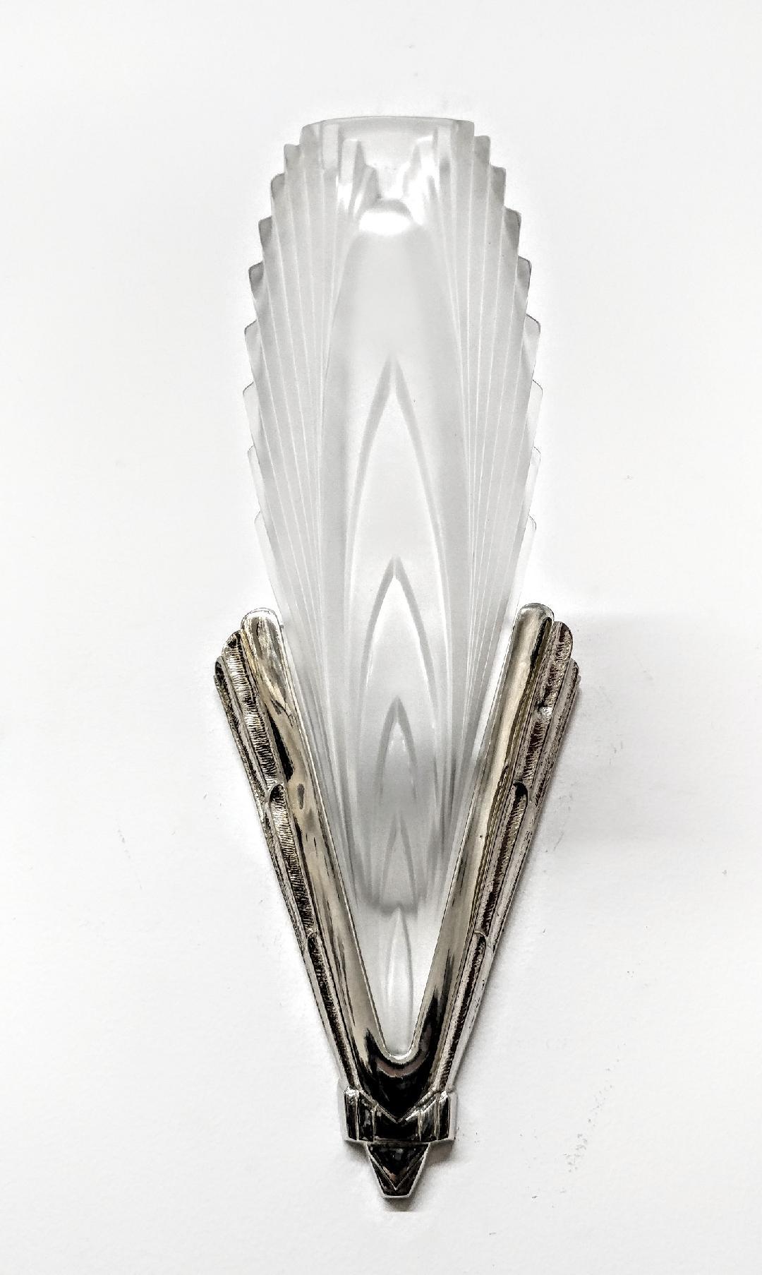 A pair of French Art Deco wall sconces in great condition. In clear frosted molded glass shades in a feather motif design held by matching bronze brackets. Sconces have been re-plated in nickel and rewired for U.S. standards. Each sconce