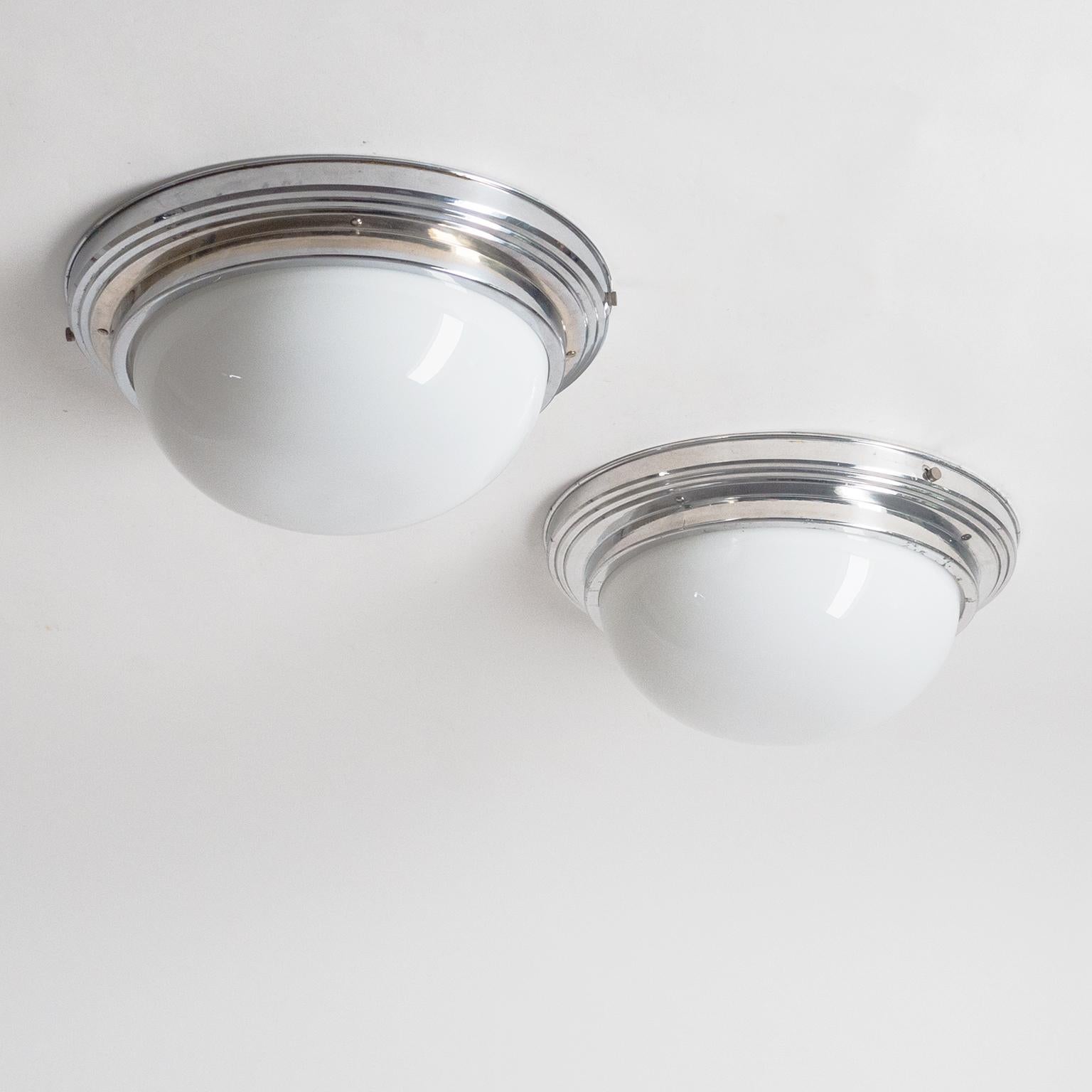 Pair of French Art Deco ceiling or wall lights from the 1930s-1940s. Matching pair, the only difference being that one backplate is made of polished aluminum while the other is chromed brass. Two brass and ceramic E14 sockets each with new wiring.