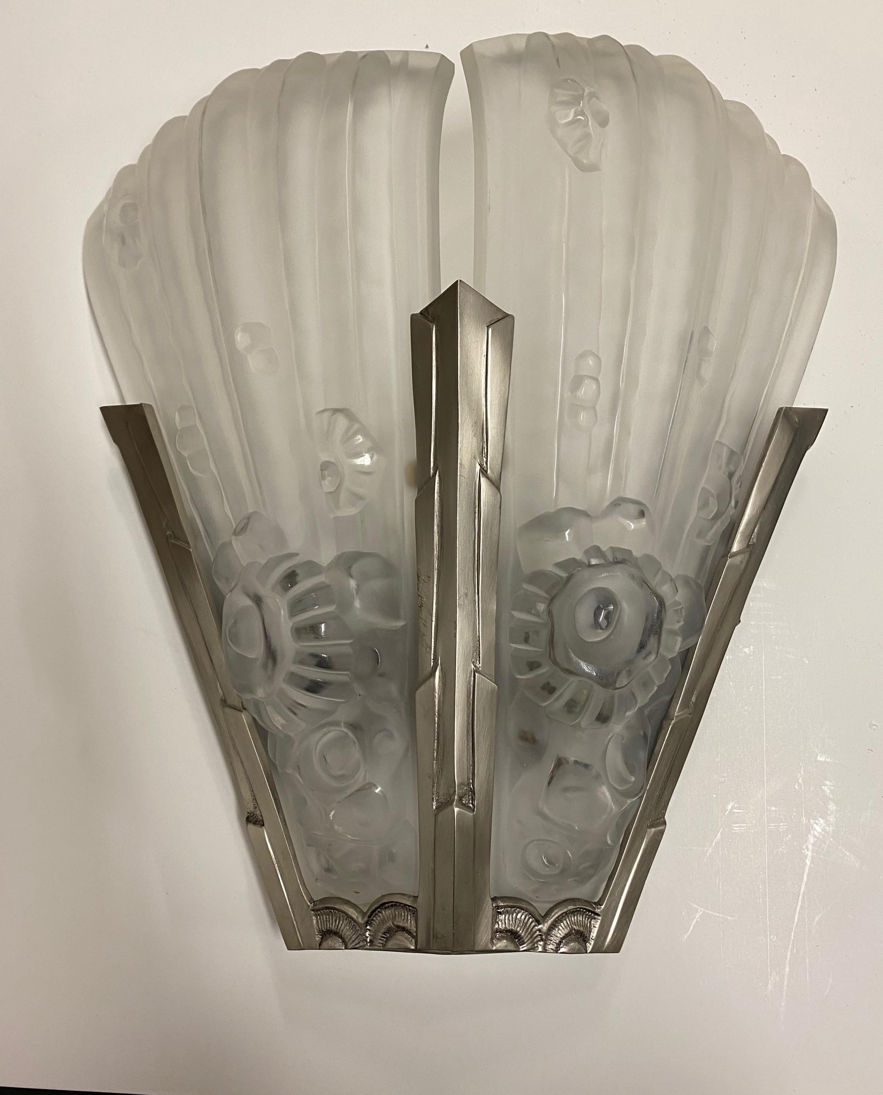 A pair of French Art Deco wall sconces by French artist Genet et Michon in clear frosted glass shades with floral and geometric motif details. Each sconce take two glass panels. Mounted in polished geometric nickel frame. Re-plating upon request.