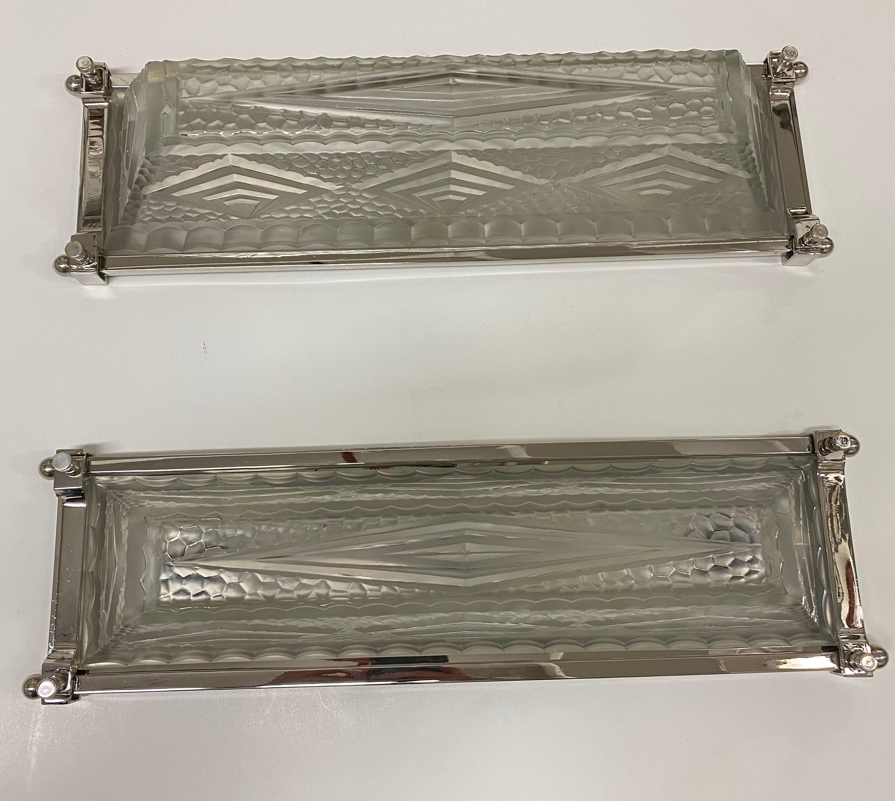 Pair of French Art Deco sconces. With clear frosted glass shades having intricate geometric motif details throughout. Held by a polished nickel plated design frame. Can be hung vertically or horizontally. Has been re wired for American use with two