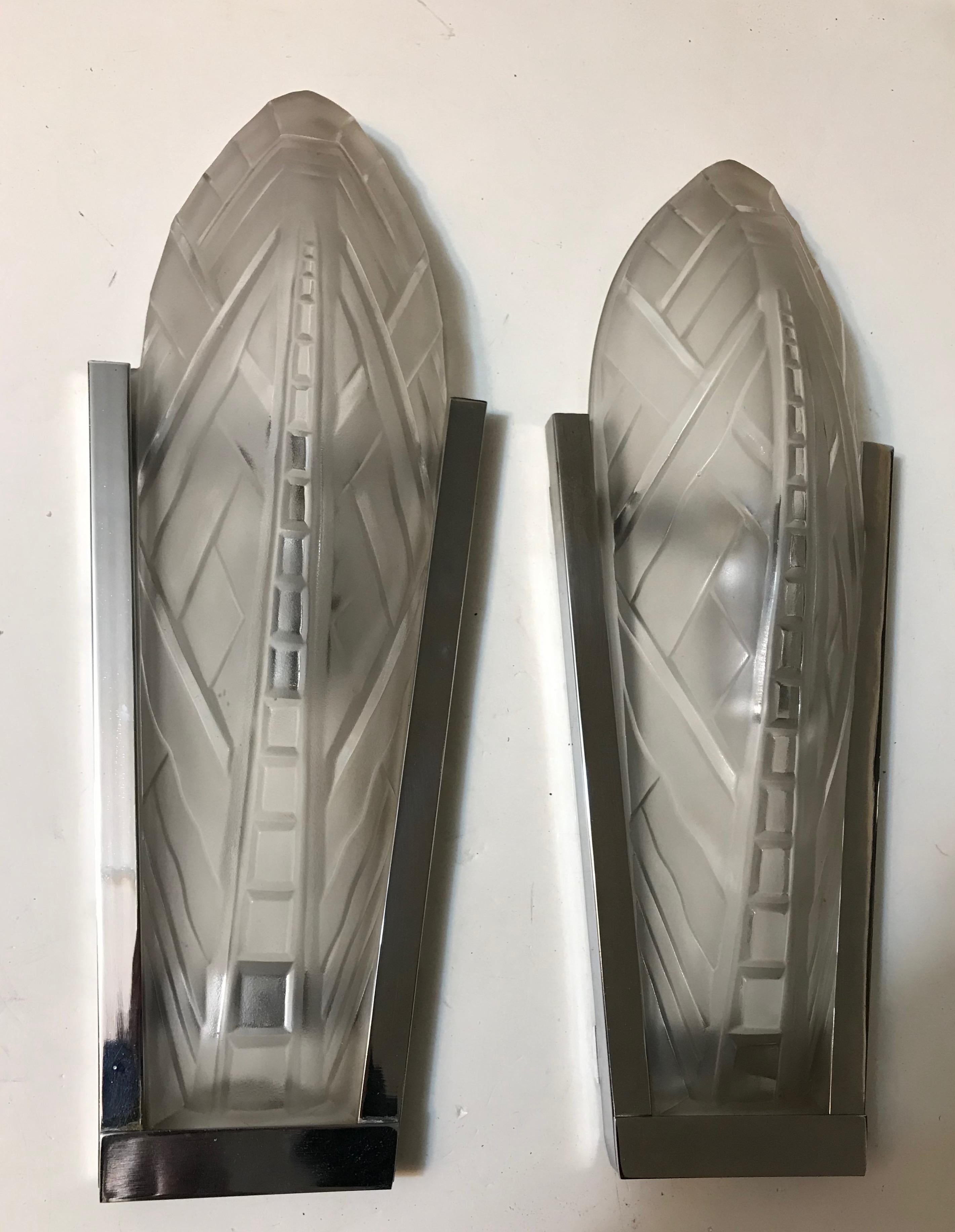 Pair of French Art Deco wall sconces signed by famous French artist Sabino. Clear and frosted molded glass shades with geometric motif held by nickel frames. Has been re wired for America use with one candelabra socket having a max watt of 60 watts