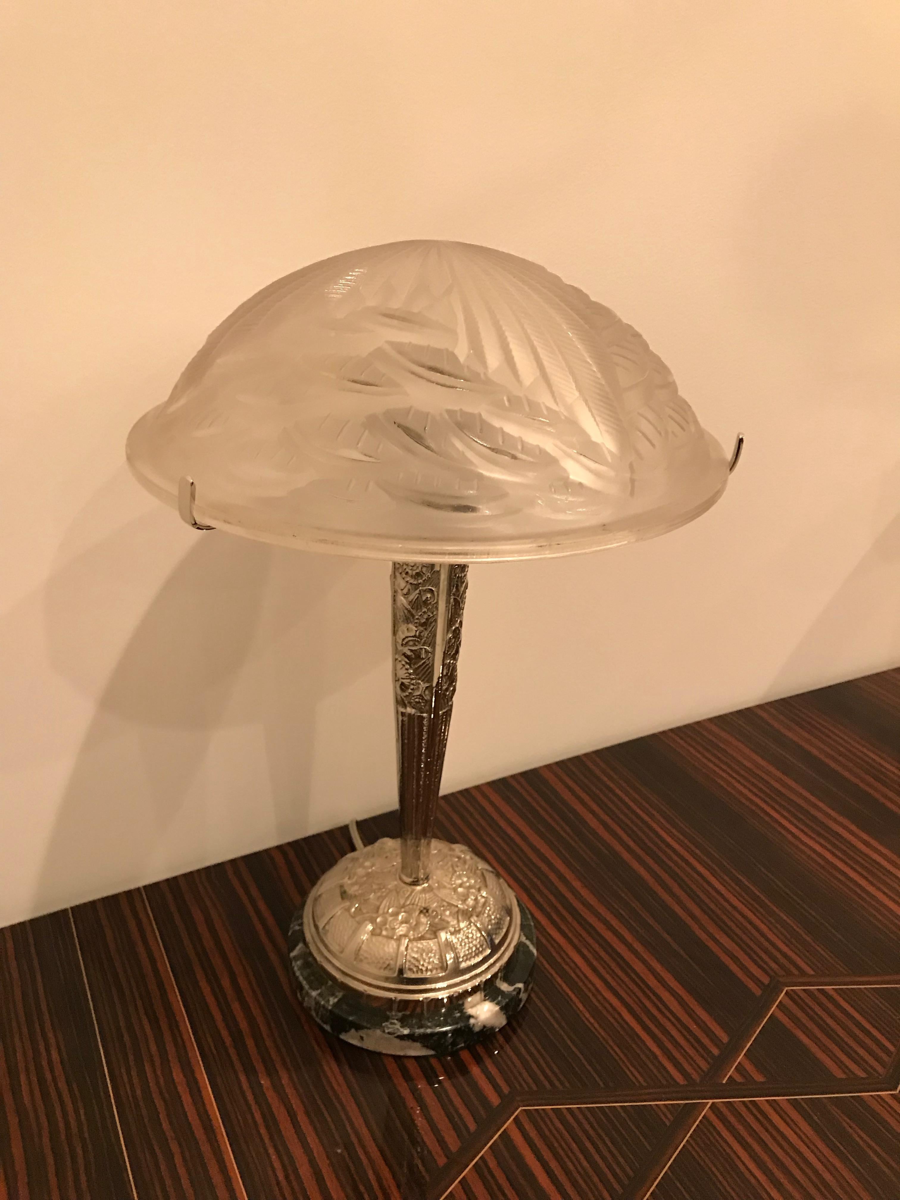 A pair of French Art Deco table lamps signed by the French artist Charles Schneider. The shades are enhanced by geometric motif in clear frosted glass with polished details. Held by matching floral geometric polished nickel design frame on marble.