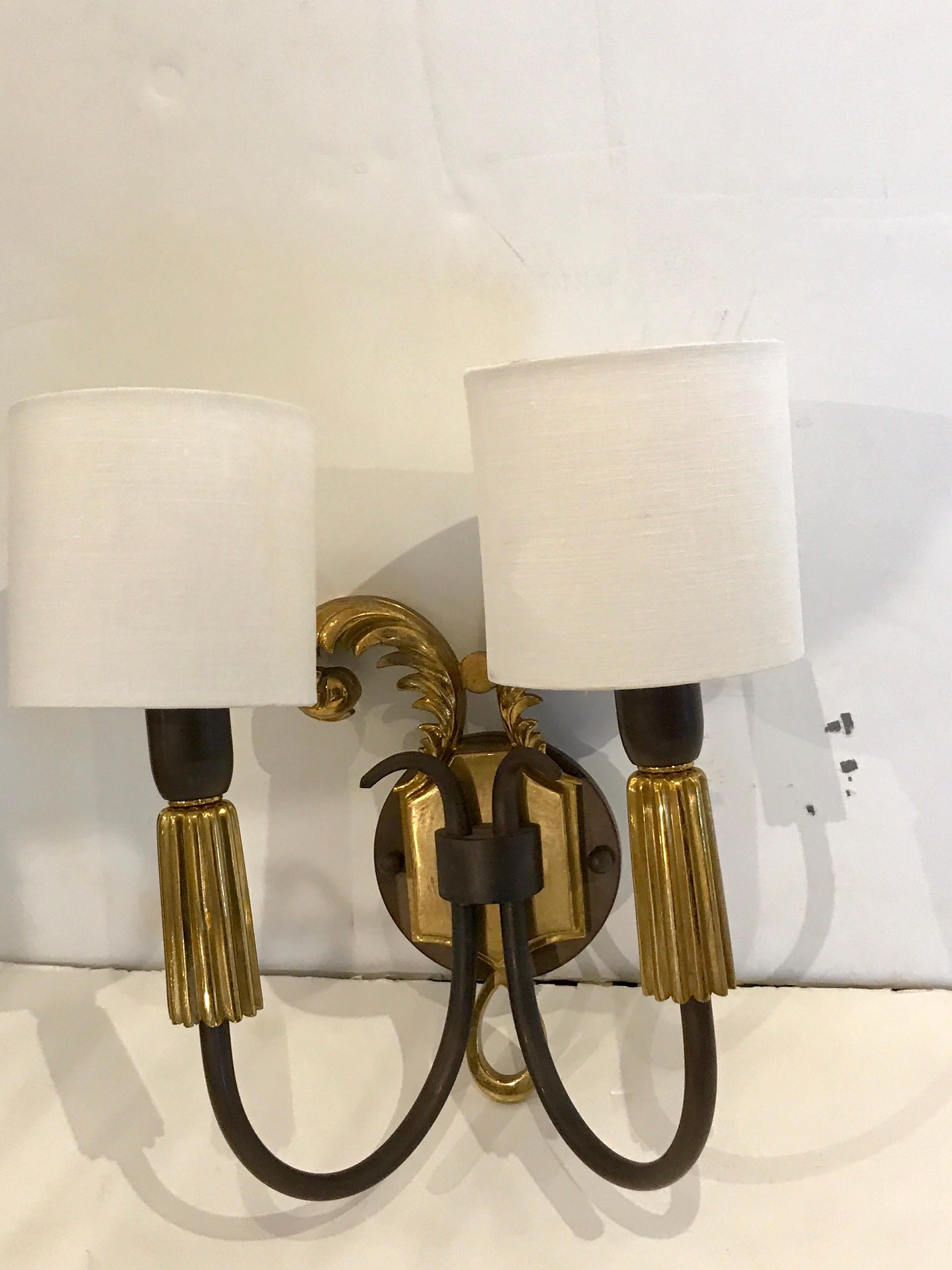 A pair of French Art Deco gilt and patinated bronze wall sconces, each one fitted with two lights. Shades for display purposes only. Newly wired. Backplate measures: 10