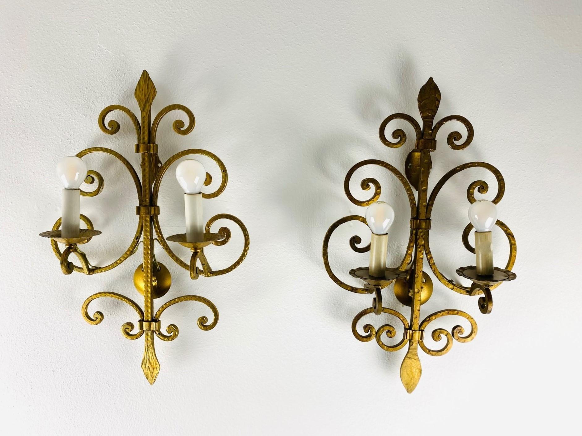 
A pair of large hand-crafted gilt iron two-arm electrified wall sconces, France, 1930s. Both sconces are in fine vintage condition, gilt very well preserved, beautiful aged patina, no damages.
Measures: Height 17.50