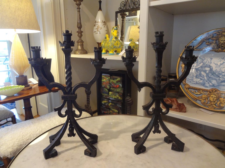 Stunning pair of French Art Deco hand forged wrought iron candleholders or lamps with Greek key feet. This pair of lamps is attributed to Charles Piguet, circa 1925. This pair could be wired to create a fabulous pair of lamps or converted to