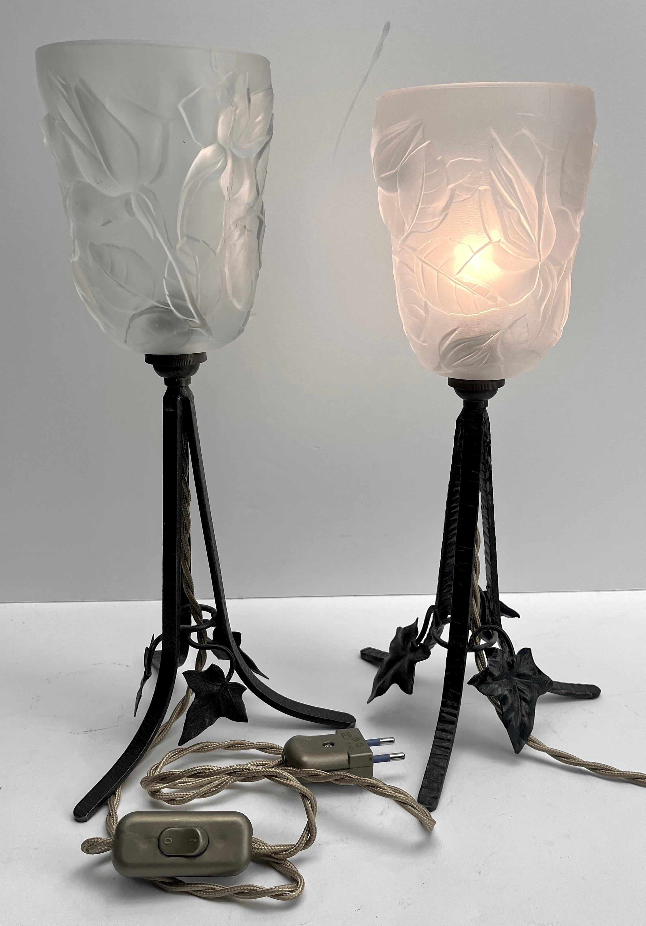 Une magnifique paire de lampes françaises. Les supports sont fabriqués à la main en fer forgé patiné noir et martelé de motifs floraux. Le travail du métal est d'excellente qualité.
Elles sont surmontées d'ombres lumineuses en pâte de verre