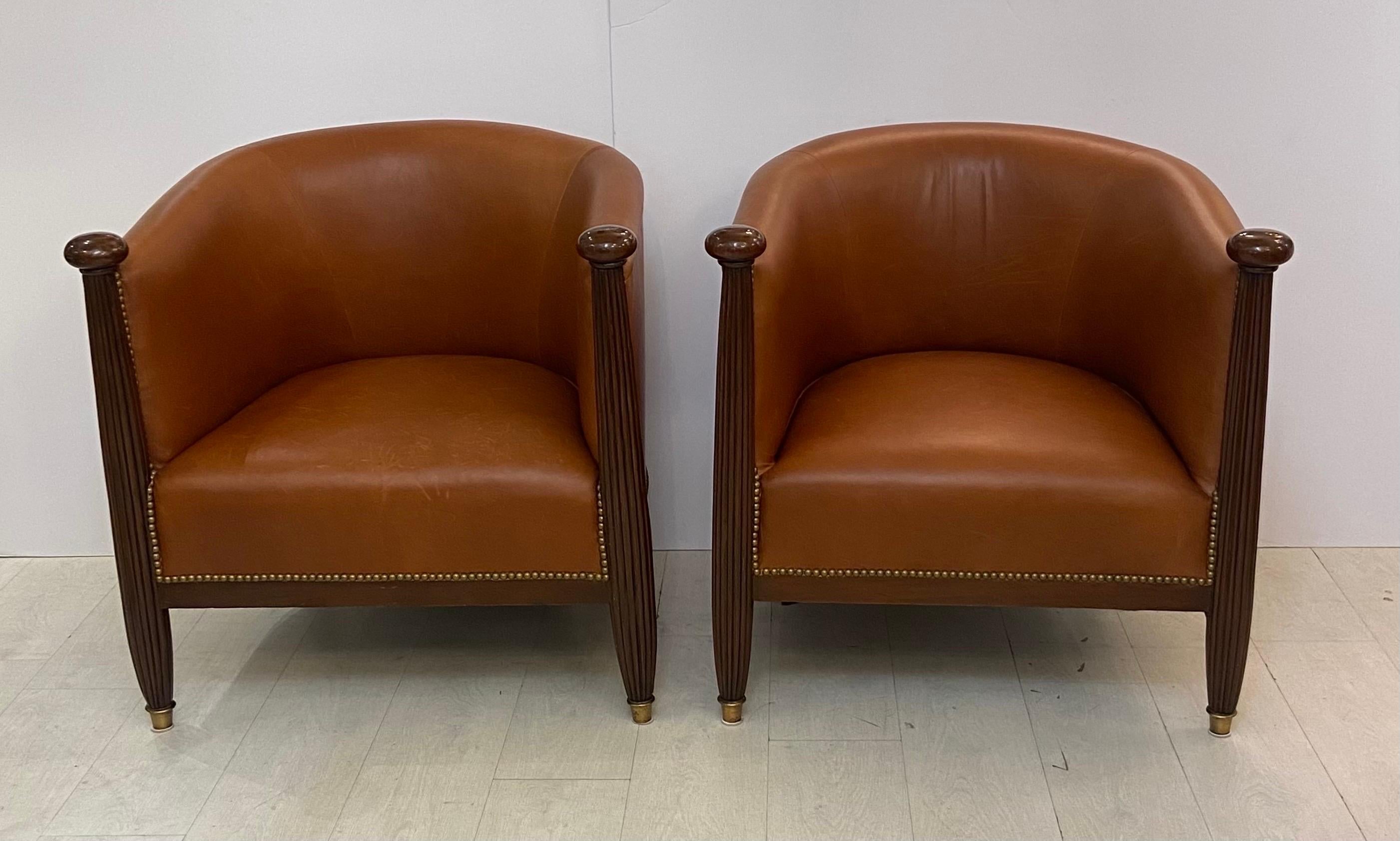 A very fine pair of period French Art Deco chairs with wonderfully carved front rails that extend upward to large mahogany hand grips. The Hand carved reeded mahogany is finally detailed and continues down to the floor and Terminates in brass caps,