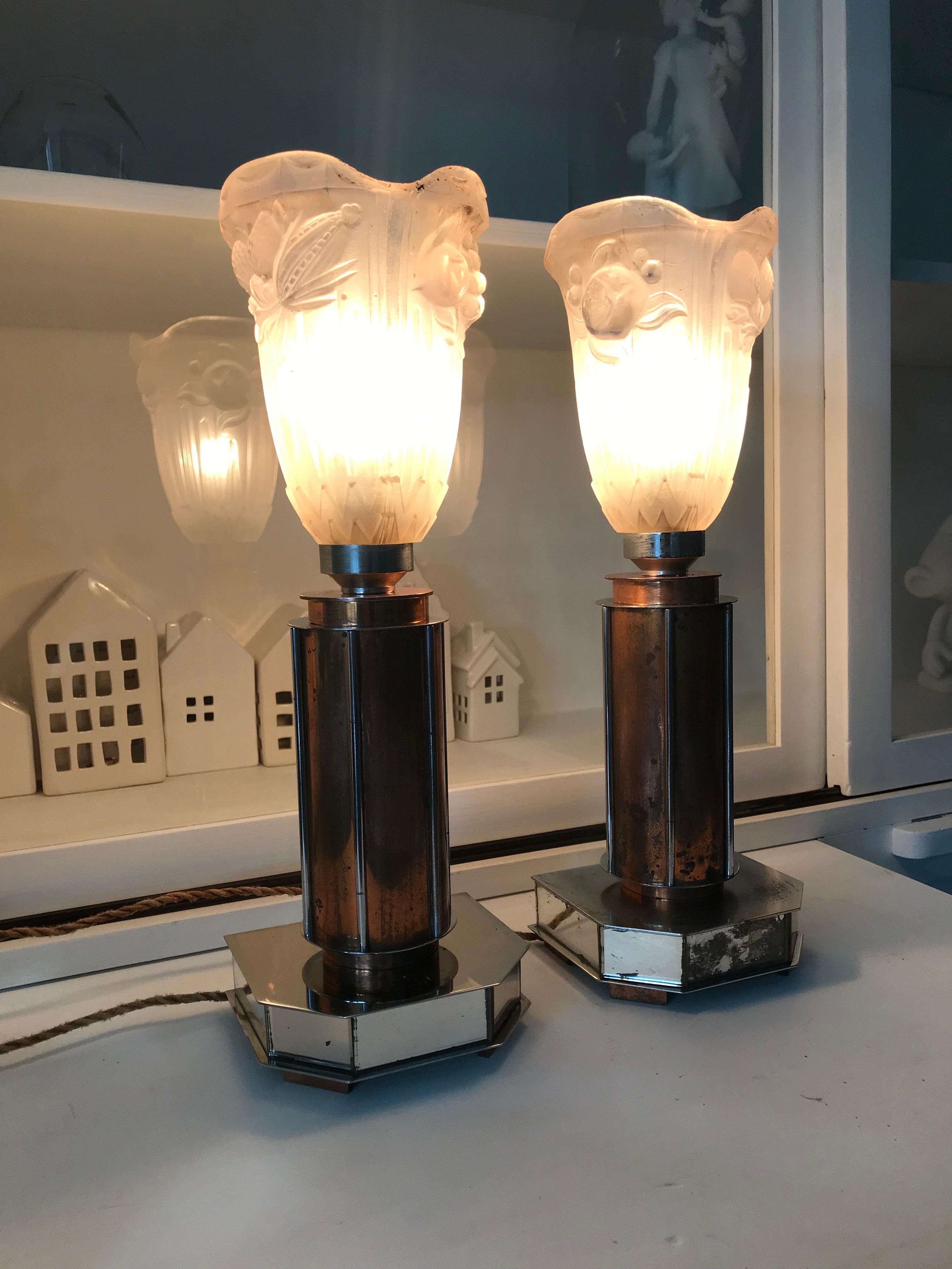 Rare pair of cylindrical design table lamps with glass shades by P. Gilles.

These stylish Art Deco table lamps are built up on geometrical bases with four copper feet. The chromed base comes with small mirror panels on all sides and rising from