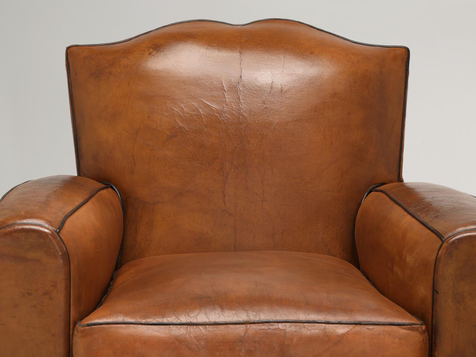 Pair of French Art Deco Moustache club chairs still maintaining their original leather covering. During our comprehensive conservation process, our inhouse Old Plank upholstery department, will adhere a heavy-duty fabric to the backside of the