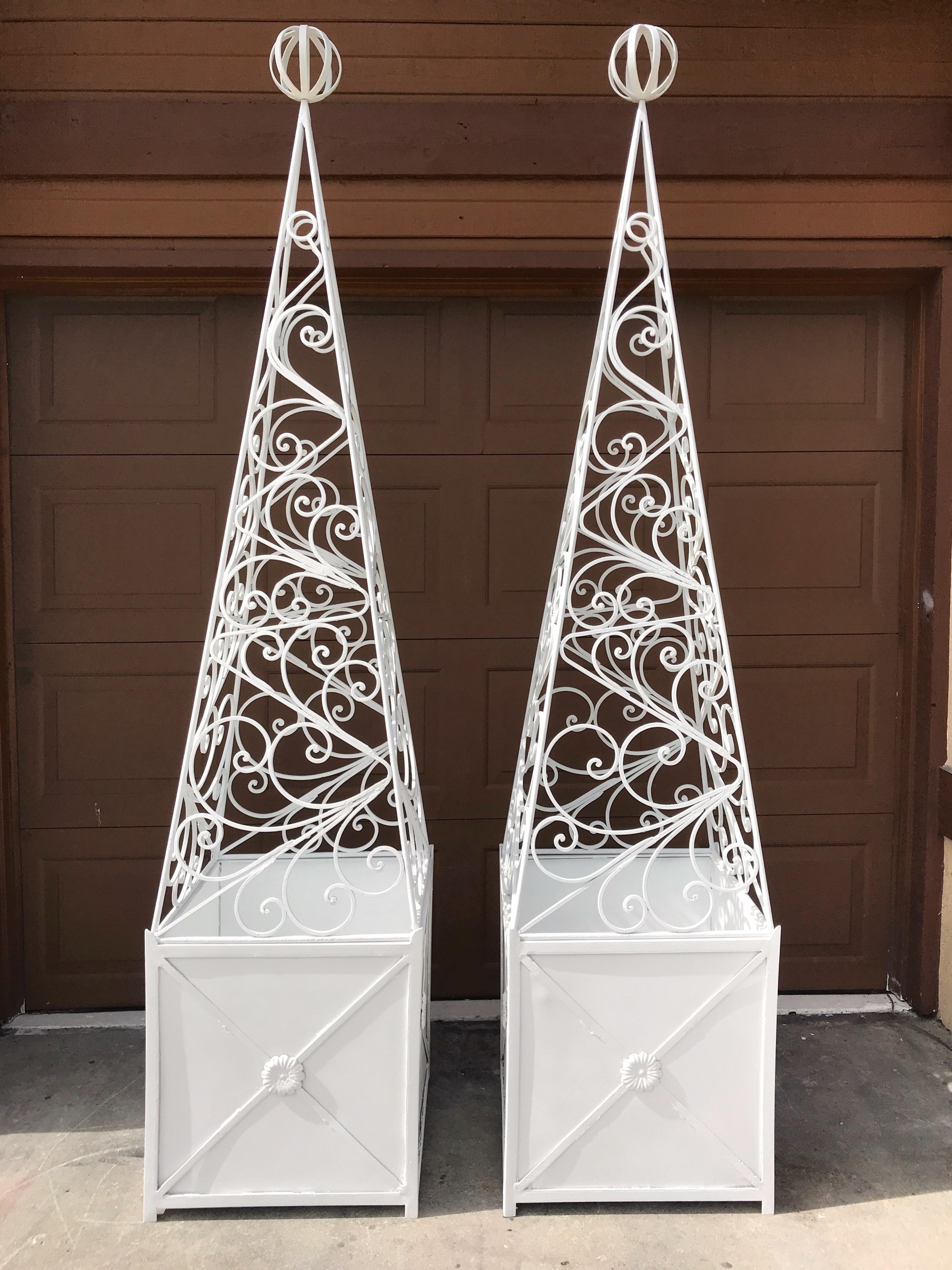 Pair of French Art Deco neoclassical wrought iron obelisk planters, each one of substantial size, in two parts, with removable pyramidal tops, on a lower cube base
The tops alone measure 21