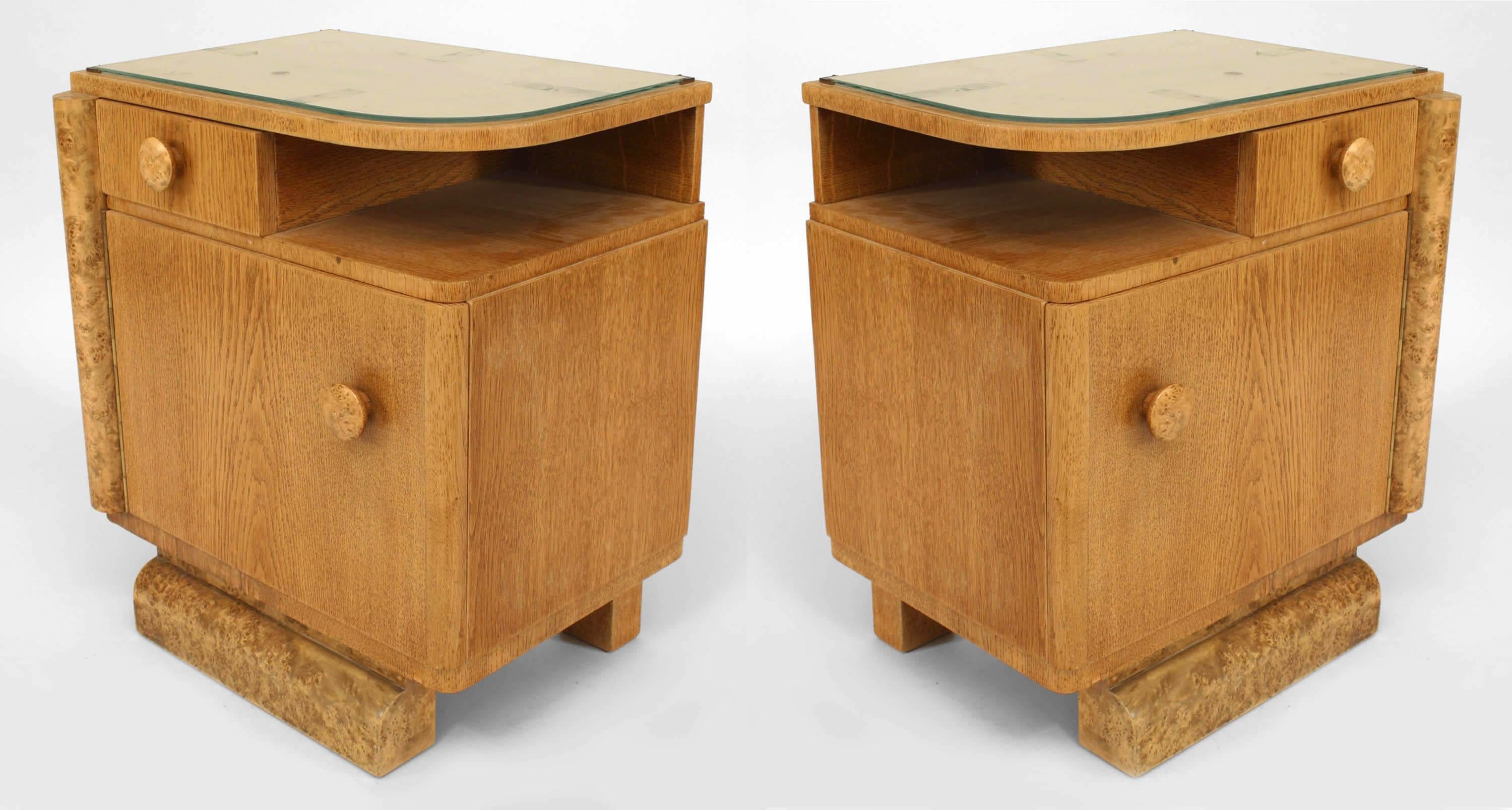 Pair of French Art Deco oak bedside commodes with burl wood trim, a small shelf, one drawer, and a large door with a glass top. (PRICED AS Pair)
