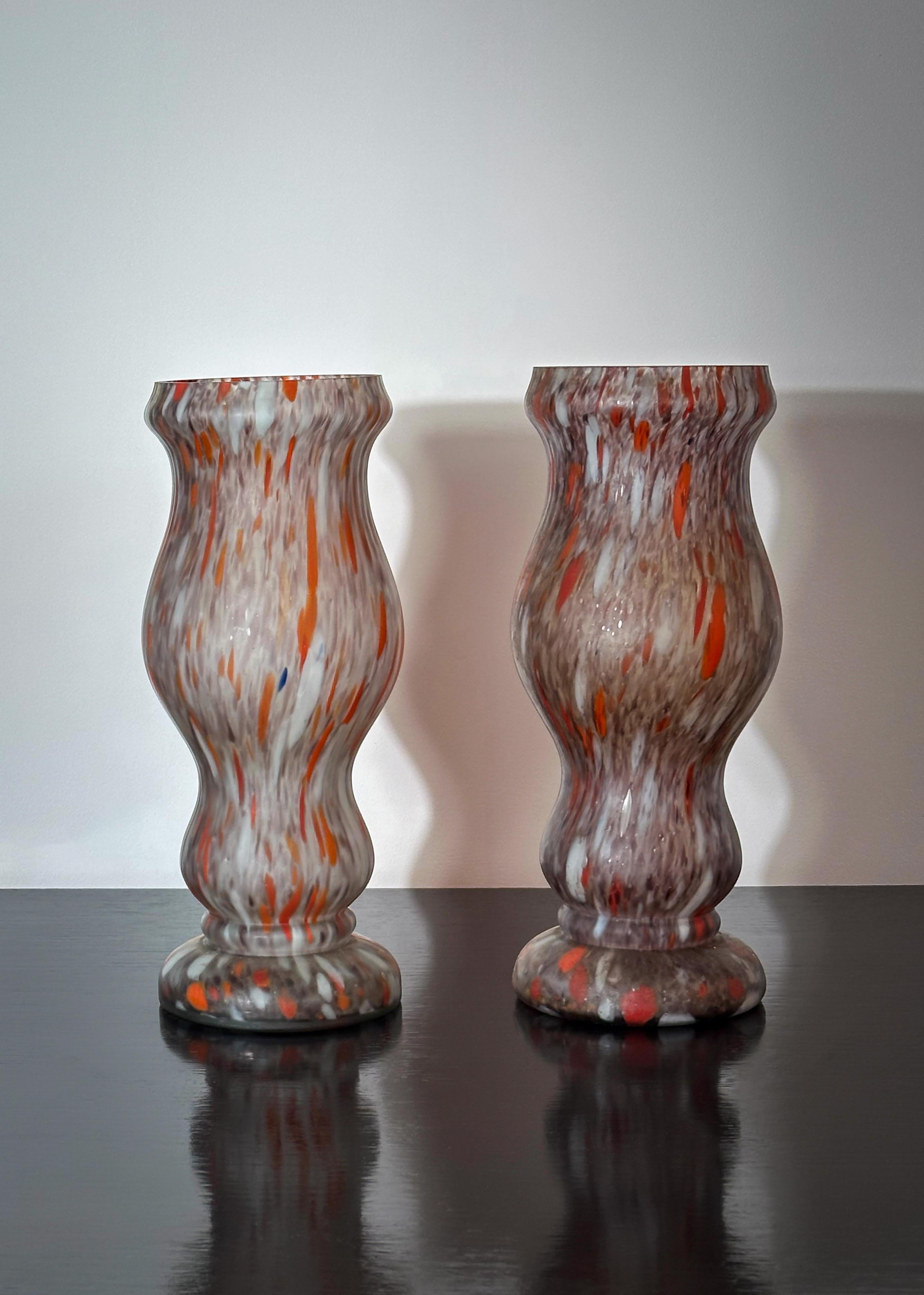 Questa coppia di vasi in vetro incamiciato Art Deco francese, realizzati intorno agli anni '30, mette in mostra la raffinata maestria dell'epoca. Modellato a forma di balaustro liscio e ondulato, ogni vaso è realizzato con la tecnica del vetro