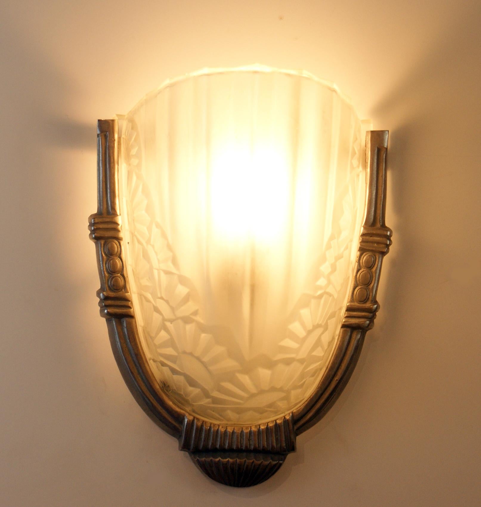 Beautiful French Art Deco scones signed “Degué” on the curved frosted glass shades with floral motif design, mounted on a geometric nickel frame.
Each sconce accommodate one candelabra bulb (60 Watt max), for a total of 120 Watts.
Can be delivered