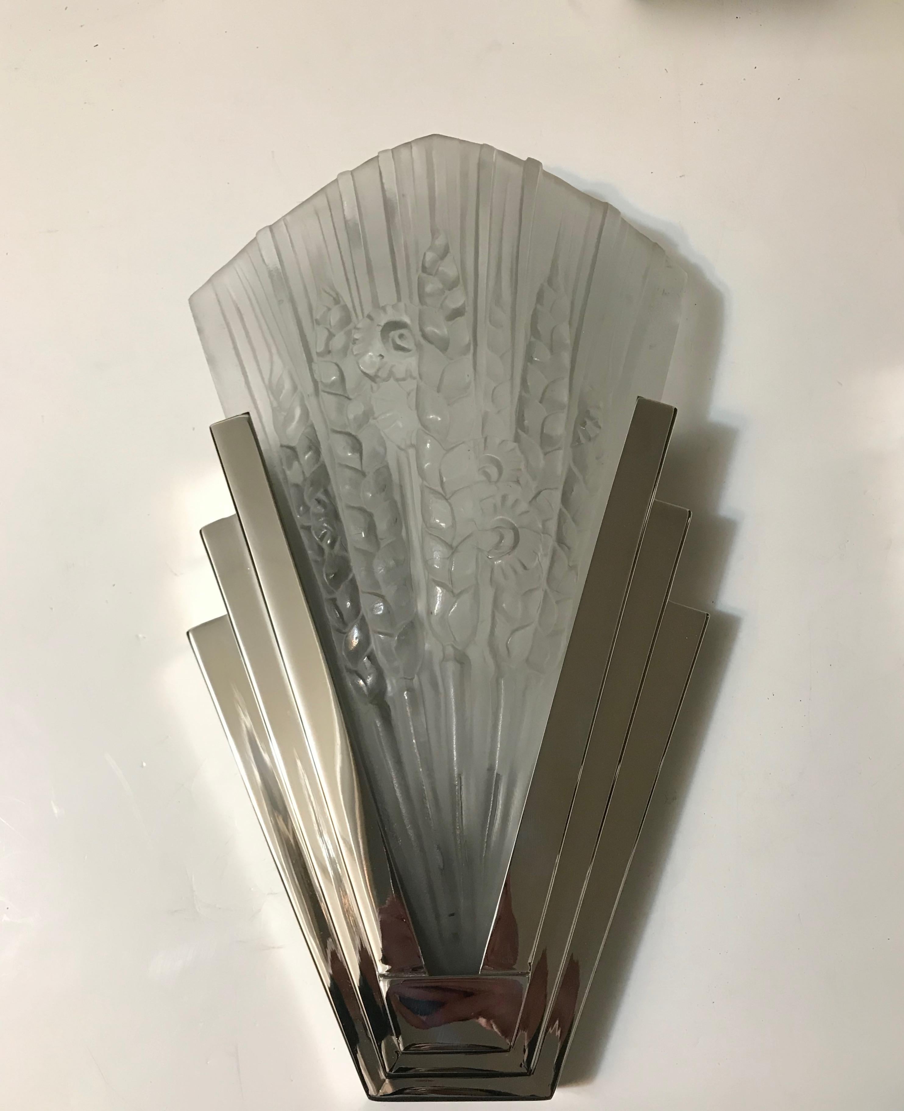 Pair of French Art Deco skyscraper sconces. Having beautiful clear frosted glass panels with floral motif. Held by polished nickel skyscraper design frames. With incredible deco details throughout. Has been rewired for American use. Each sconce