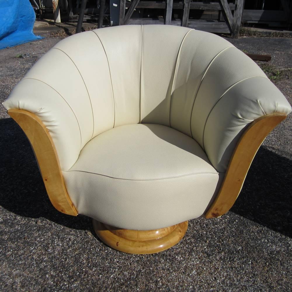 A pair of French Art Deco style lounge chairs. Generous cushioning and curves, and a pedestal base of burled wood. Arms are cushioned.