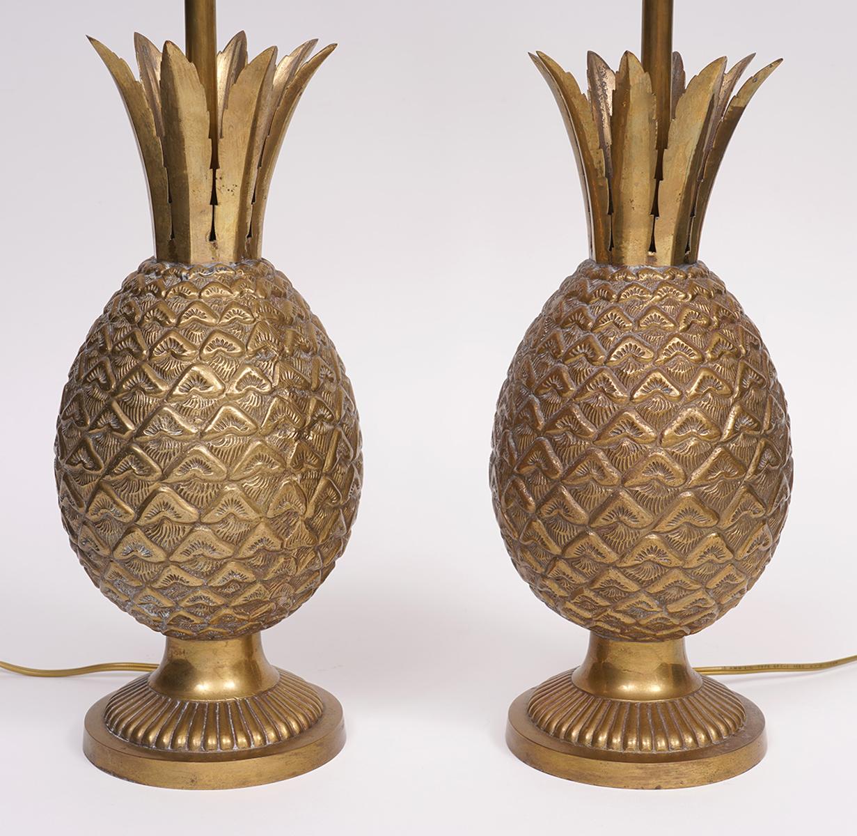 A fine pair of midcentury Art Deco style pineapple bronze lamps featuring stylized saw tooth leaves arranged like crowns on top of richly textured solid bronze bodies resting on circular reeded bases. Center stems with pineapple finials rise to hold