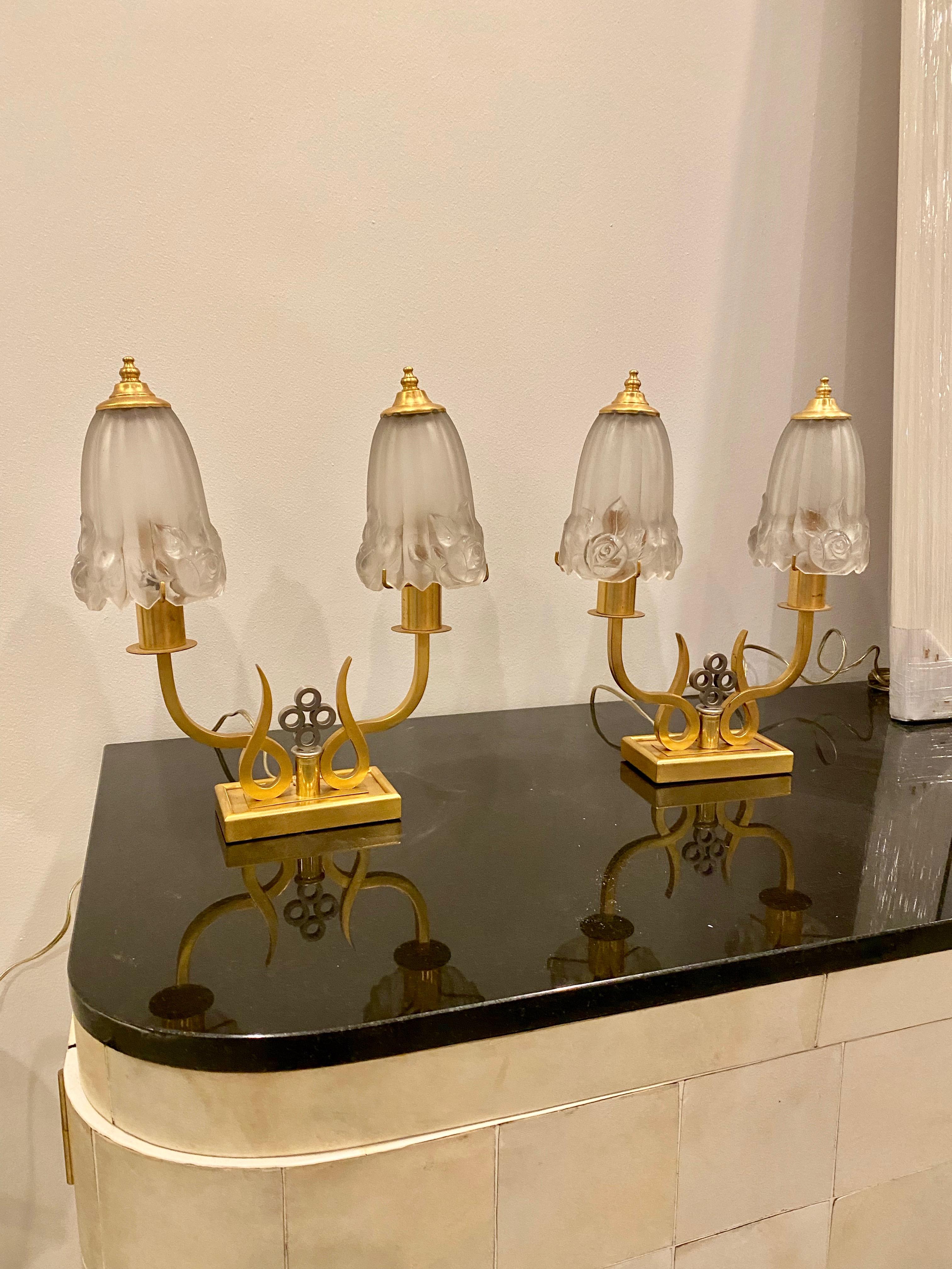 Pair of French Art Deco table lamps by G Leleu. Have four clear frosted floral shades resting on a two tone base. The two tone bases consist of geometric deco details out of brass and nickel. Has been rewired for American use with one candelabra