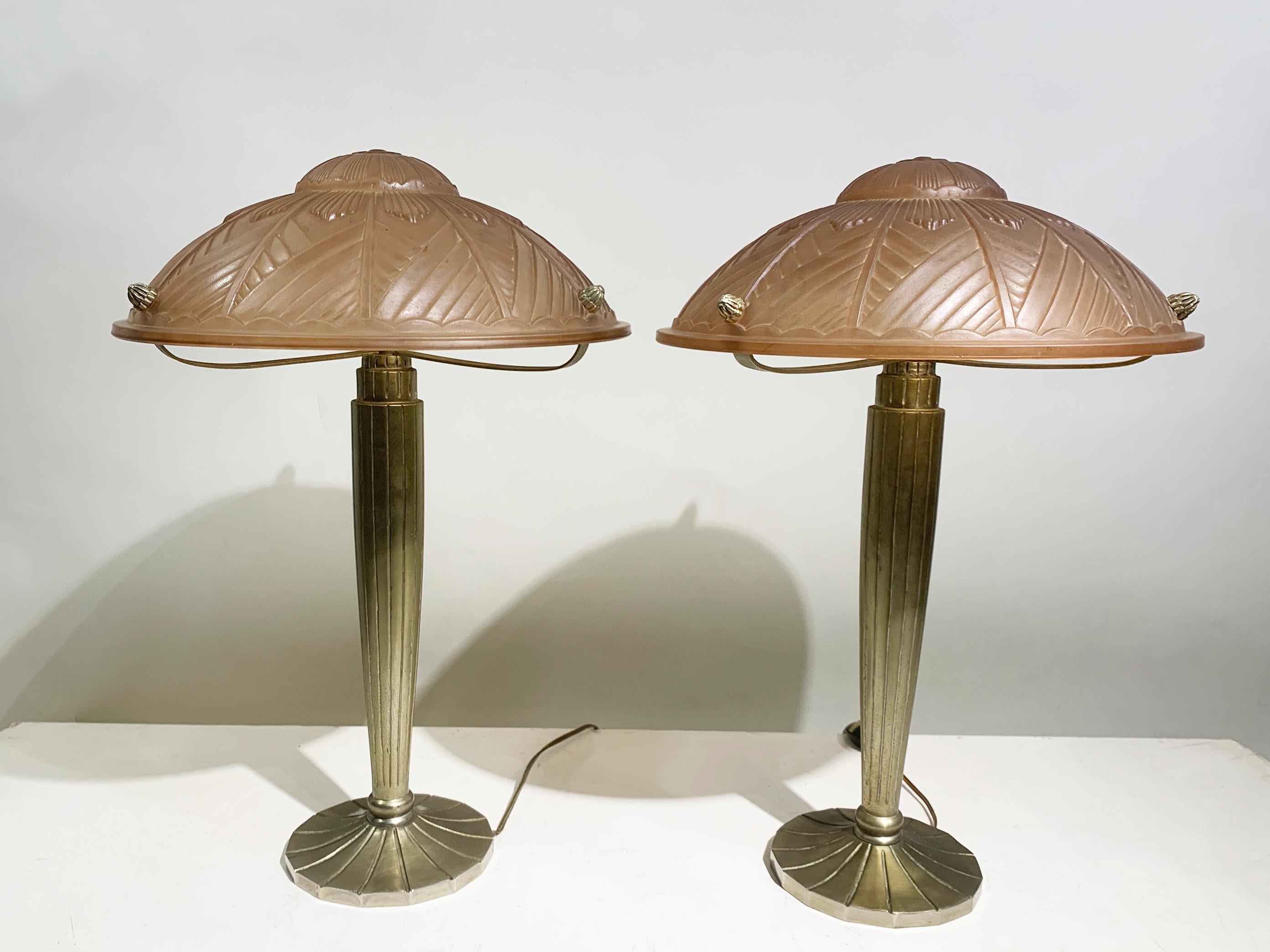 This elegant pair of French Art Deco table lamps embodies the sophisticated aesthetics of the 1930s, showcasing a harmonious blend of classic design and striking materials. Each lamp features a beautifully crafted domed shade made from pink