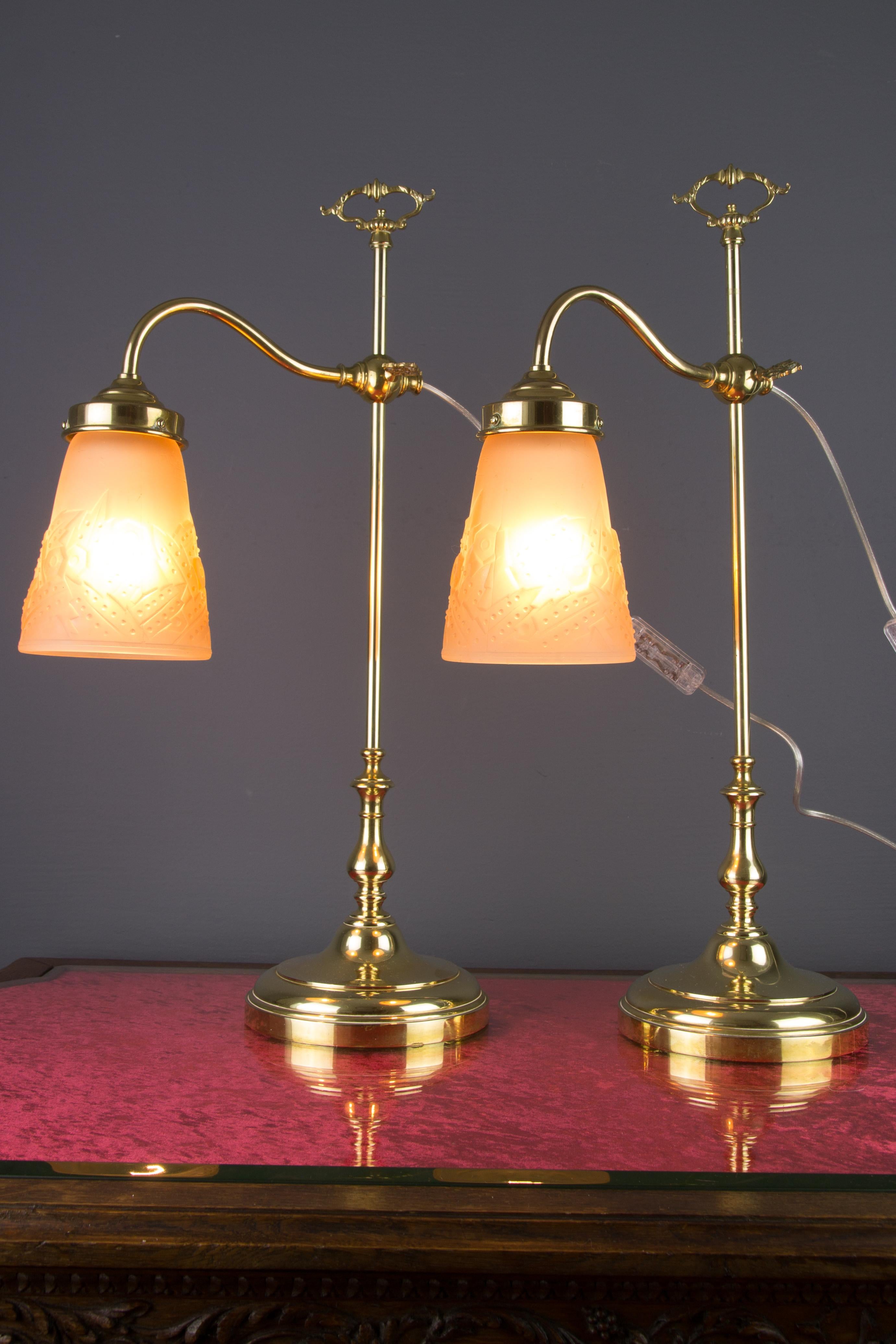 A beautiful pair of Art Deco table lamps, made of bronze and brass with light pink frosted glass shades, signed Muller Frères Luneville. Adjustable height of lamp glass shades. Each with one socket for E27 (E26) size light bulb. To the US will be