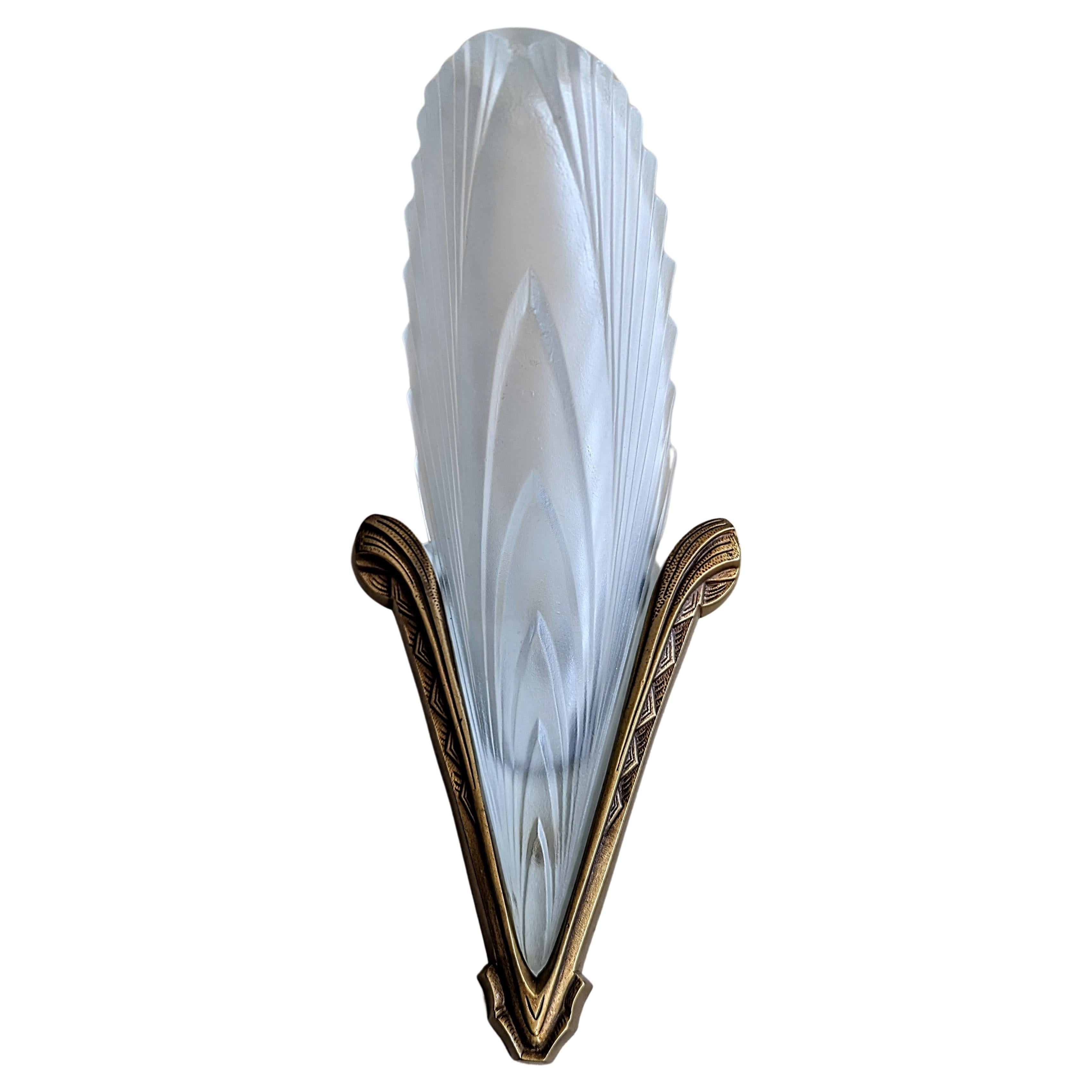 A pair of French Art Deco wall sconces in great condition. In clear frosted glass shades in a feather design held by matching golden, bronze brackets with old patina . Sconces have been rewired for U.S. standards. Each sconce accommodates one
