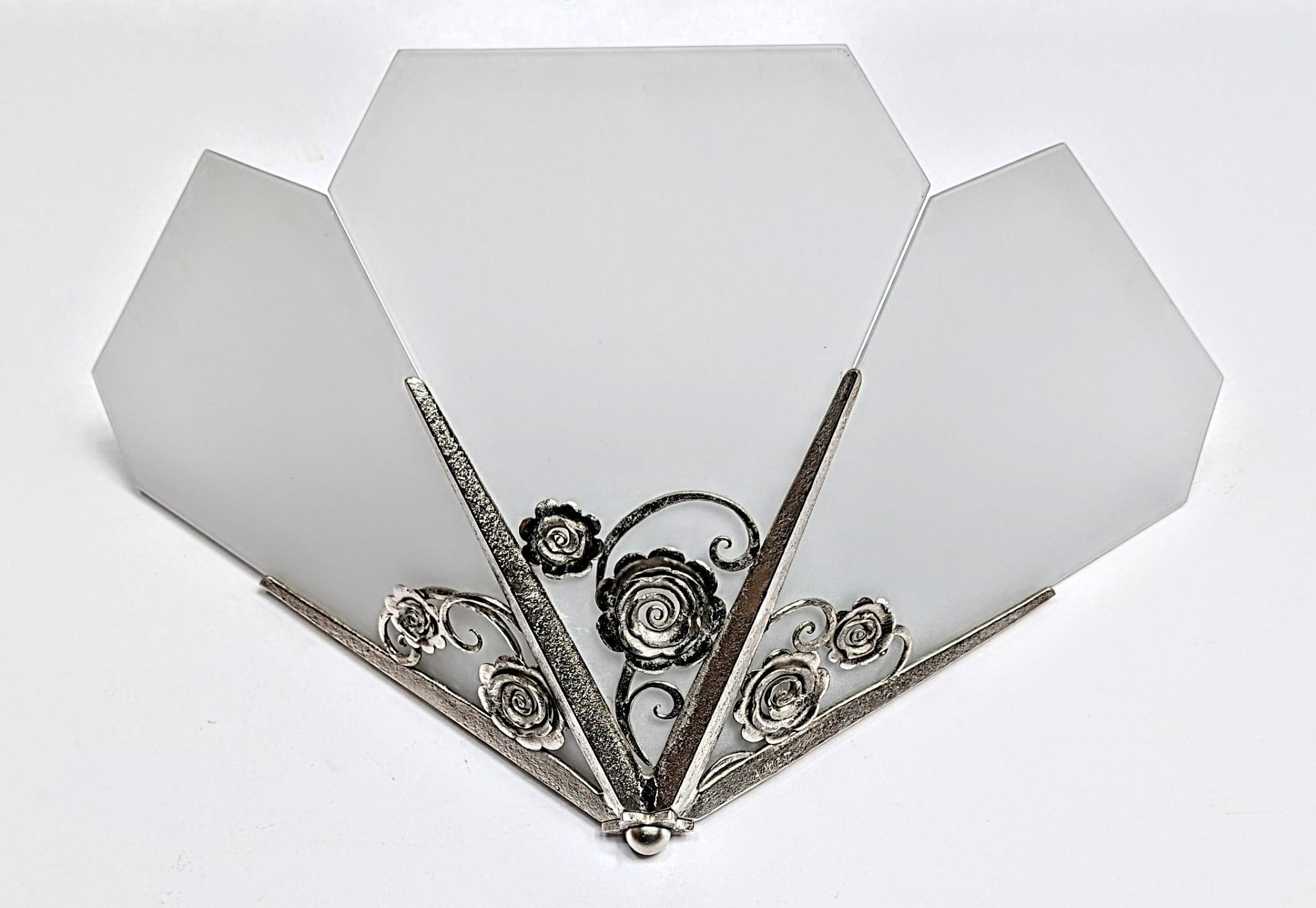 Exceptional pair of French Art Deco wall sconces signed Amiot. Hand-forged wrought iron in different textures with fine intricate leaves and flower motifs. Diamond shape frosted glass panels. Each sconce was rewired to U.S. standards, accommodating