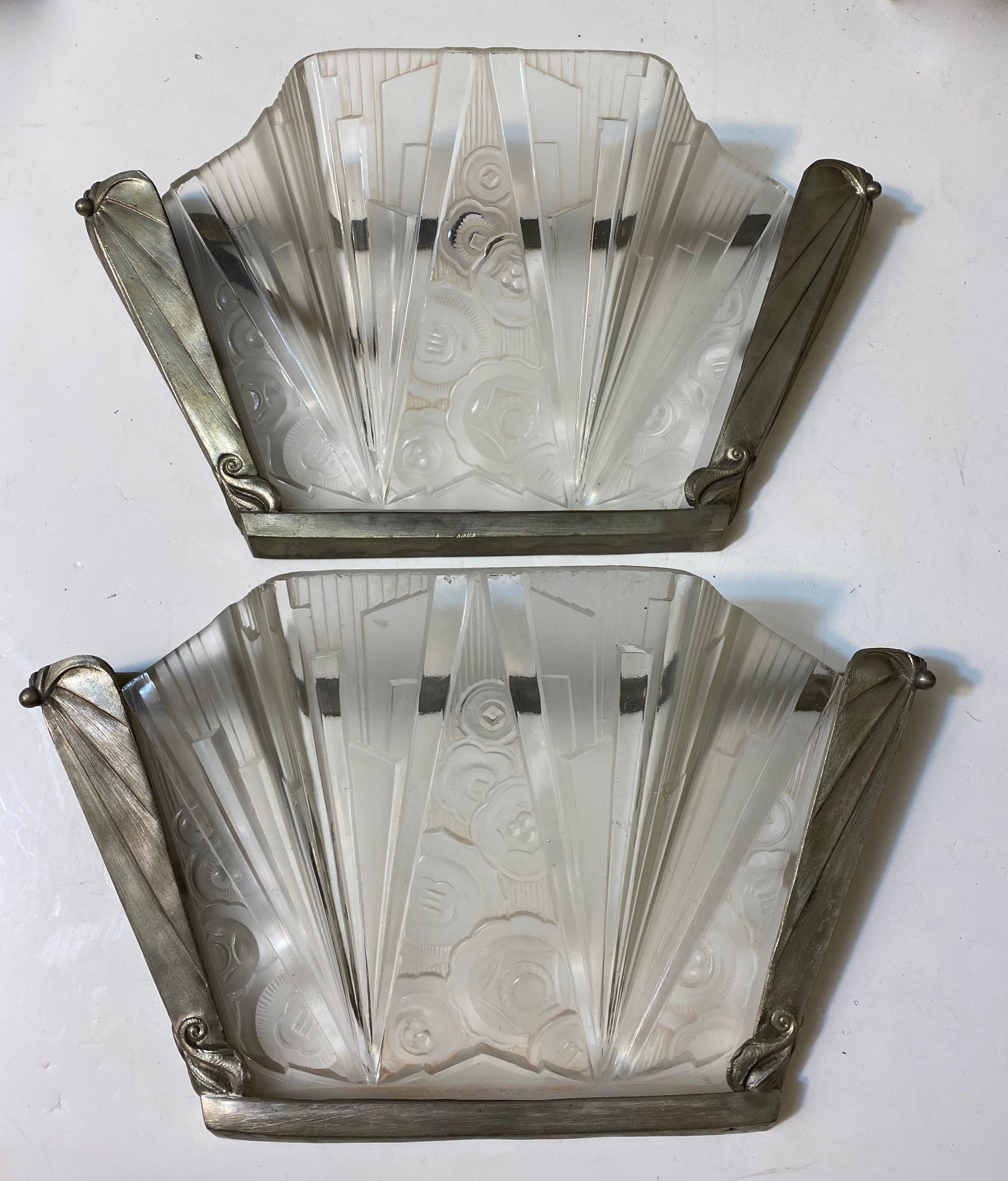 Stunning pair of French Art Deco sconce signed by Hettier Vincent. With clear frosted glass shades having intricate geometric and floral motif details throughout. The shades are held by a matching nickel geometric design frame. Has been rewired for