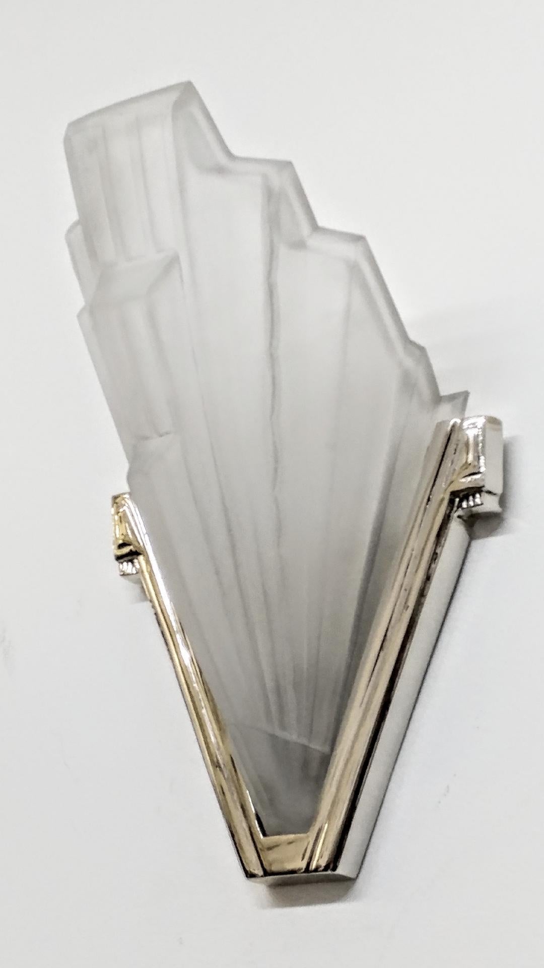 A stunning pair of French Art Deco sconces by the French artist “Sabino“ in great condition. Clear and frosted molded glass shades with Skyscraper geometric motif. Held by polished details mounted in nickeled bronze design frames. Replated in nickel