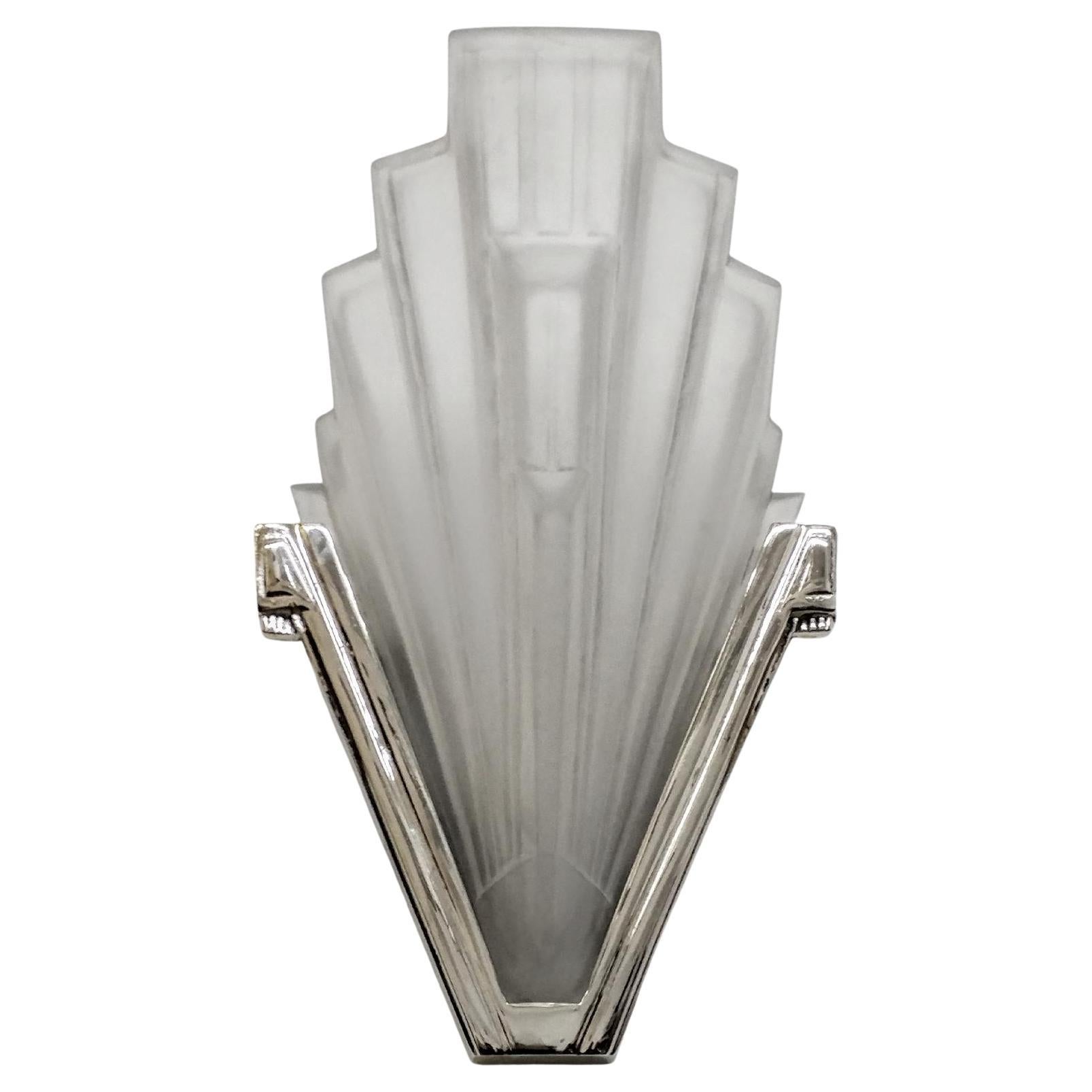 A stunning pair of French Art Deco sconces by the French artist “Sabino“ in great condition. Clear frosted molded glass shades with Skyscraper geometric motif. Held by polished nickeled bronze frames. Replated in nickel and rewired to U.S. standards