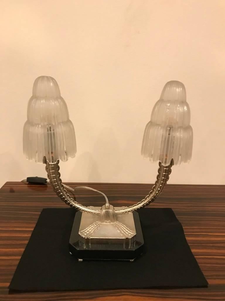 A stunning pair of French Art Deco table lamps created in the 1930s by Marius Ernest Sabino, (1878-1961). The shades are clear frosted glass with polished details referred to as the 