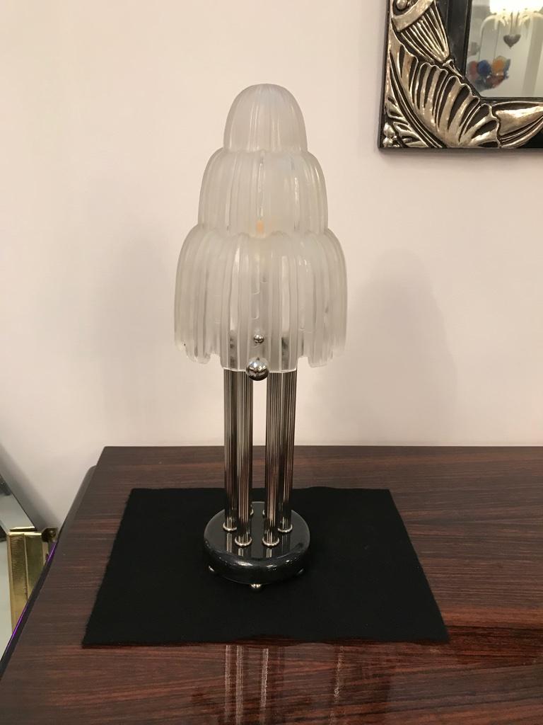 Pair of French Art Deco table lamps created by Marius Ernest Sabino, (1878-1961). The shades are clear frosted glass with polished details referred to as the 