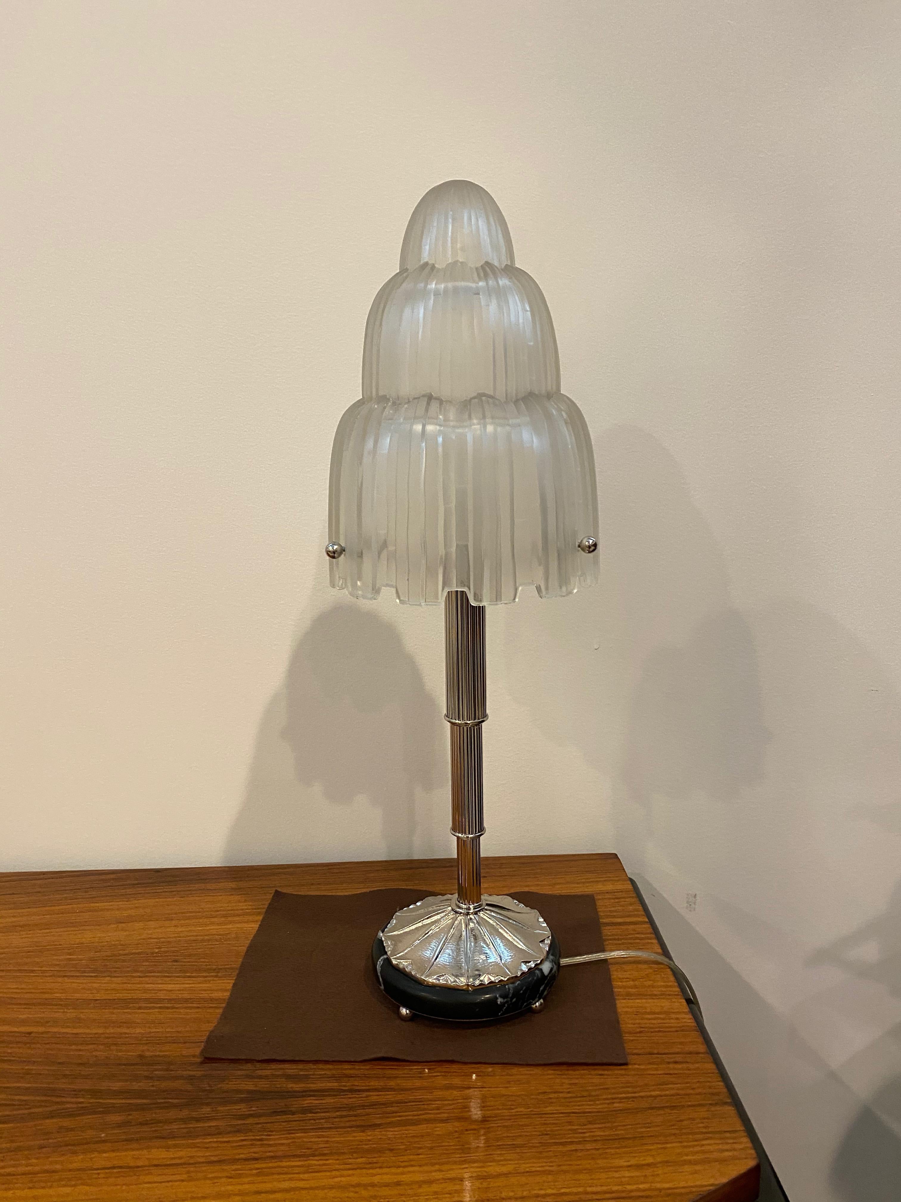 Magnificent pair of French Art Deco table lamps created by Marius Ernest Sabino, (1878-1961). The shades are clear frosted glass with polished details referred to as the 