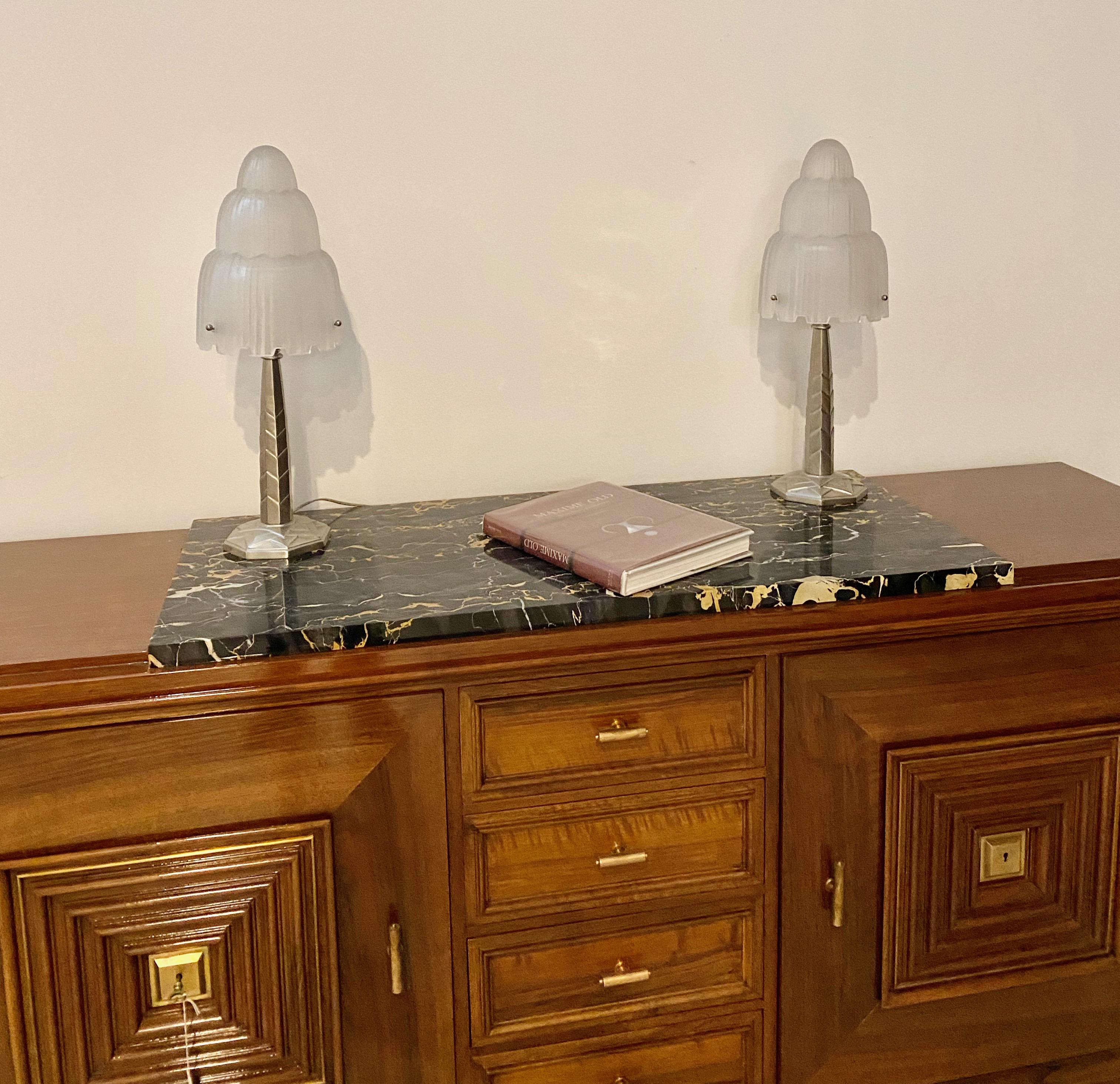 Magnificent pair of French Art Deco table lamps created by Marius Ernest Sabino, (1878-1961). The shades are clear frosted glass with polished details referred to as the 