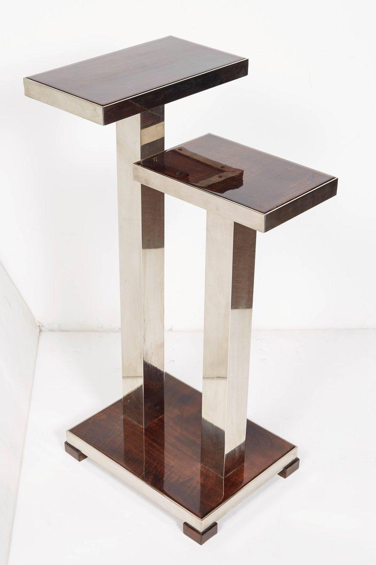 
Can be sold as a single, a pair or trio. Price listed is per table.
Pair of French modernist rectangular, two-tier tables with nickeled bronze double tubular base. Architectural in design with cubist lines, this asymmetrical table with shelves at