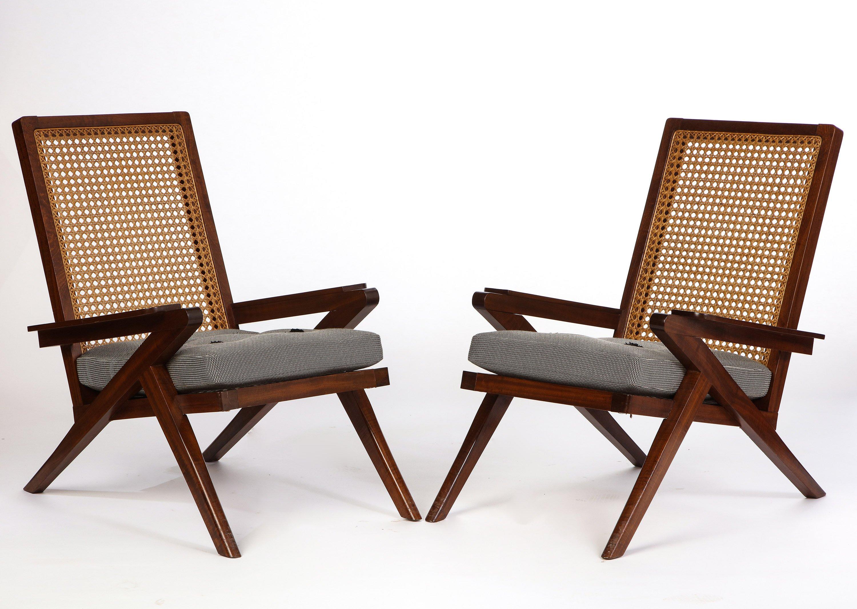 A pair of French ‘Art Moderne’ style mahogany and caned armchairs with upholstered cushions from the 20th century. These chairs are composed of a varnished mahogany structure and caned seat made comfortable with custom upholstered cushions. The
