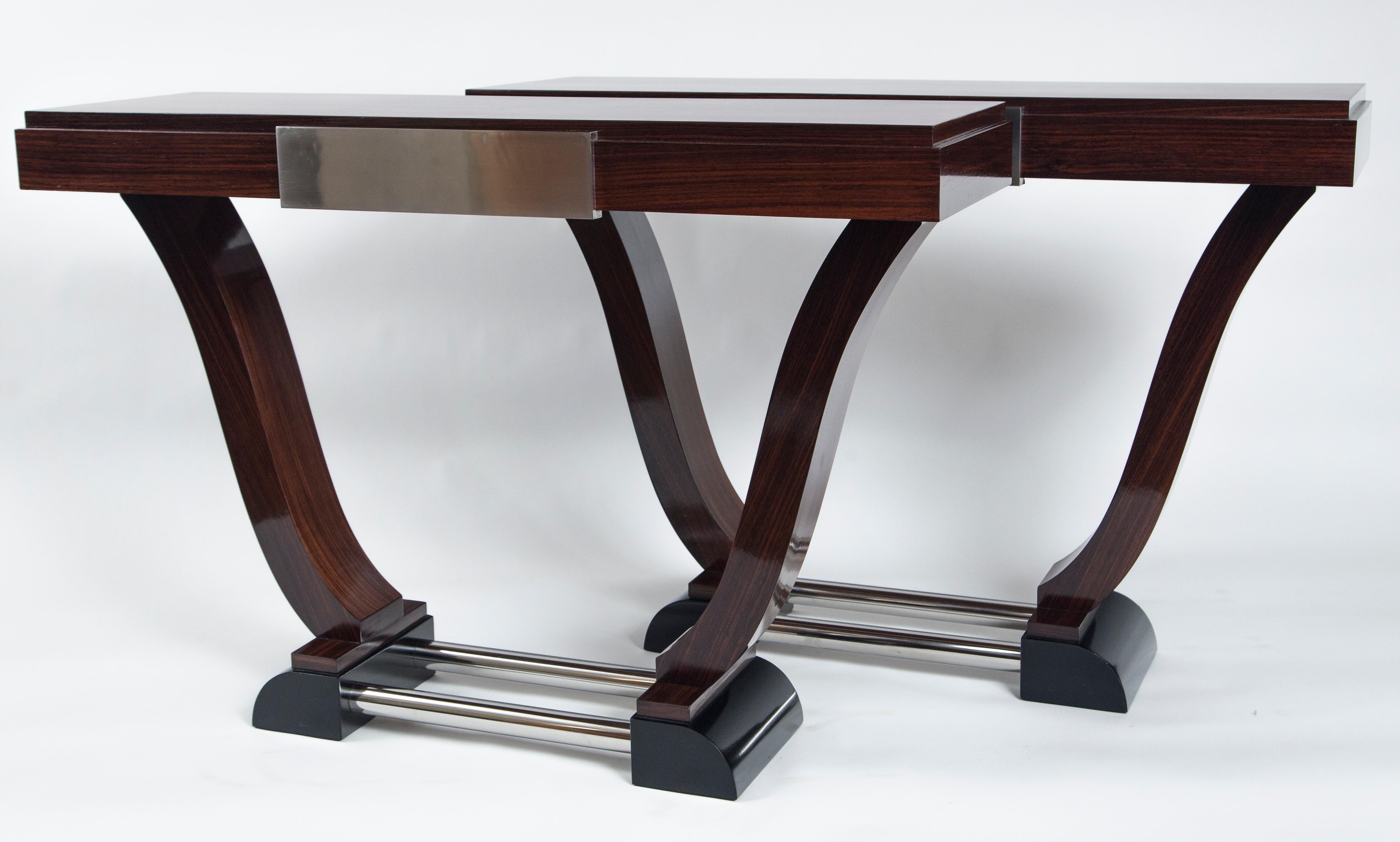 Sleek and unique pair of late Art Deco console tables in rosewood with matte nickel panel detailing in the apron of each rectangular shaped stepped plateau, finishing on vasi shaped base joined by turned nickel tubes.
Priced as a pair
Origin: