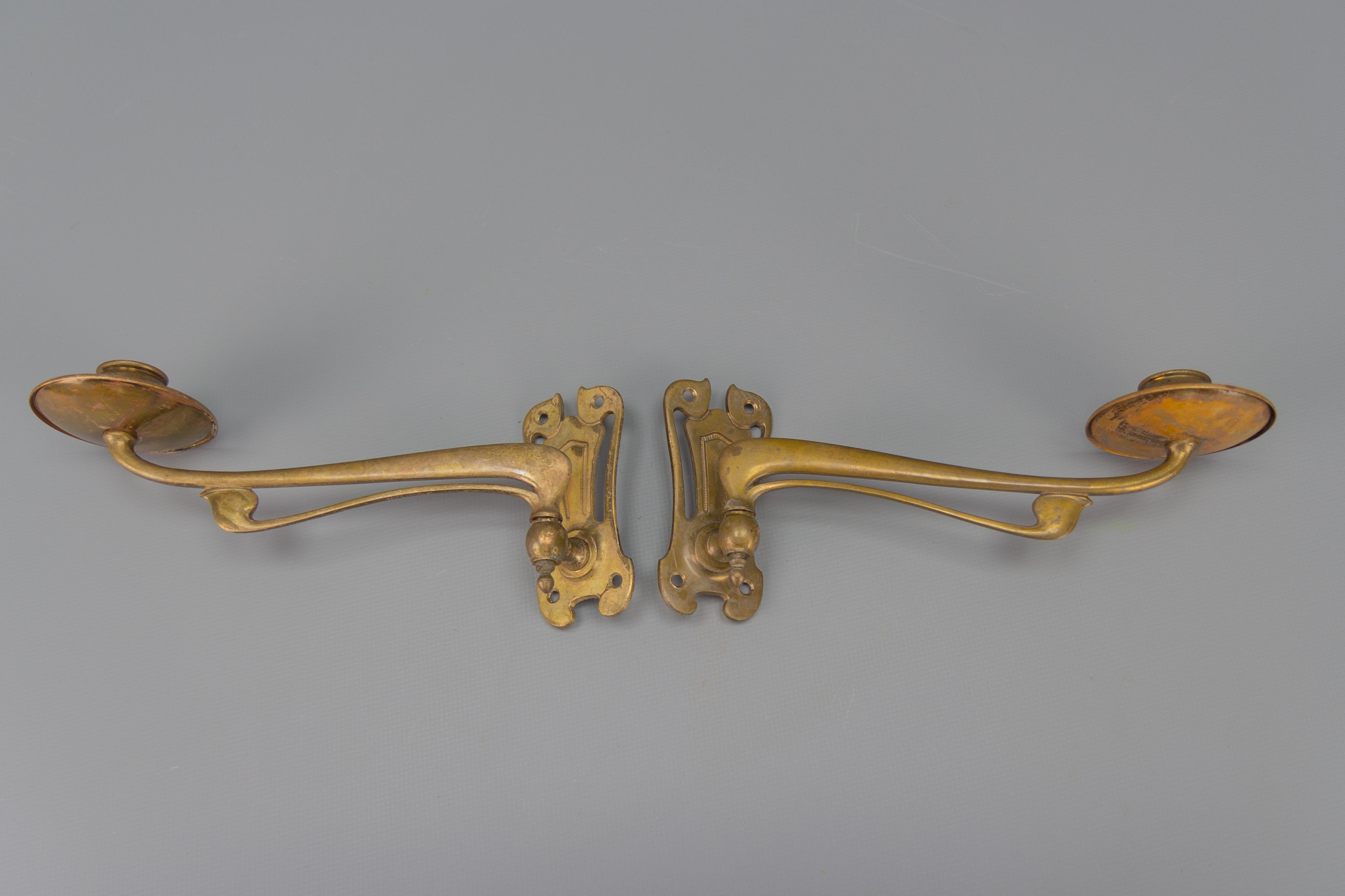 An elegant and beautiful pair of French Art Nouveau brass piano or wall sconces, swivel candleholders from circa 1920. 
Each sconce has one arm for one candle, shaped in adorable Art Nouveau-style lines. 
Dimensions: height 10 cm / 3.93 in; width 7