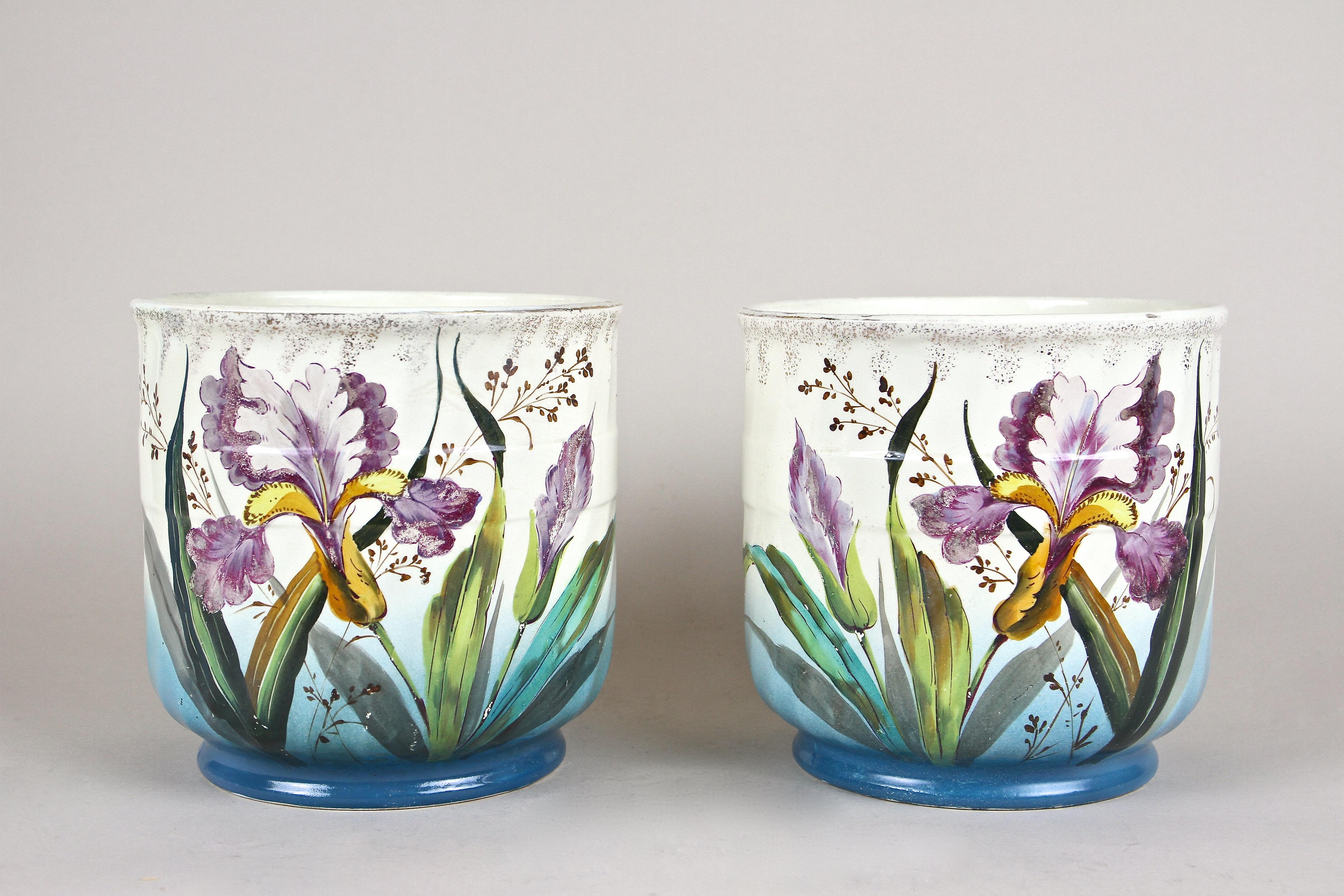 Wunderschön bemaltes Paar französischer Keramik-Übertöpfe aus dem frühen Jugendstil um 1900. Diese farbenfrohen Pflanzgefäße zeigen eine tolle Kombination aus schönen handgemalten Lilien in fantastischen Lila-, Gelb- und Grüntönen und einem blauen