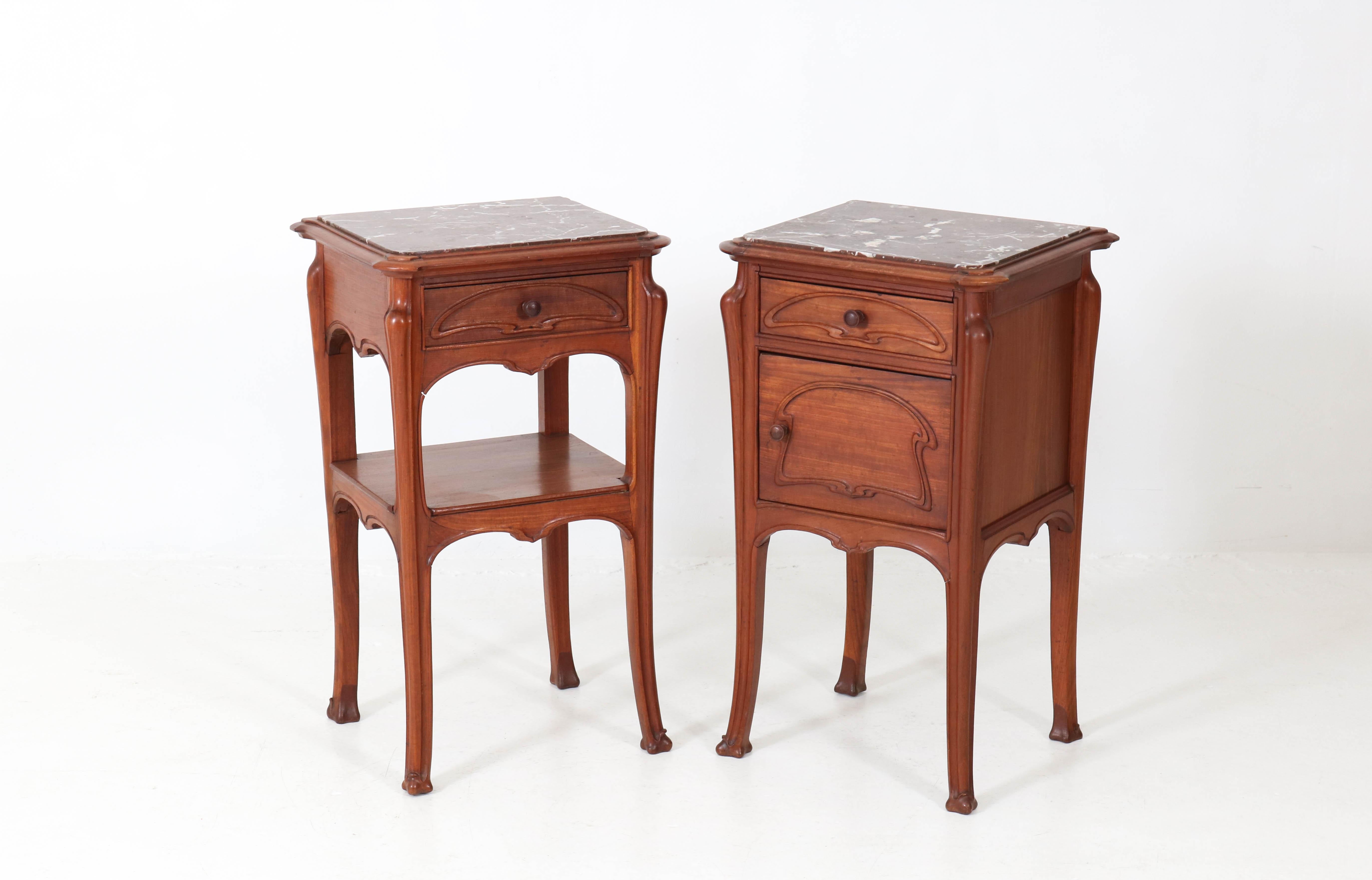 Offered by Amsterdam Modernism:
Elegant pair of French Art Nouveau nightstands or bedside tables.
In the style of Louis Majorelle.
Solid mahogany with original marble tops.
Striking French design from the 1900s.
In good original condition with minor