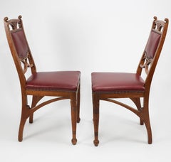 A pair of French Art Nouveau oak dining chairs with whiplash side stretchers