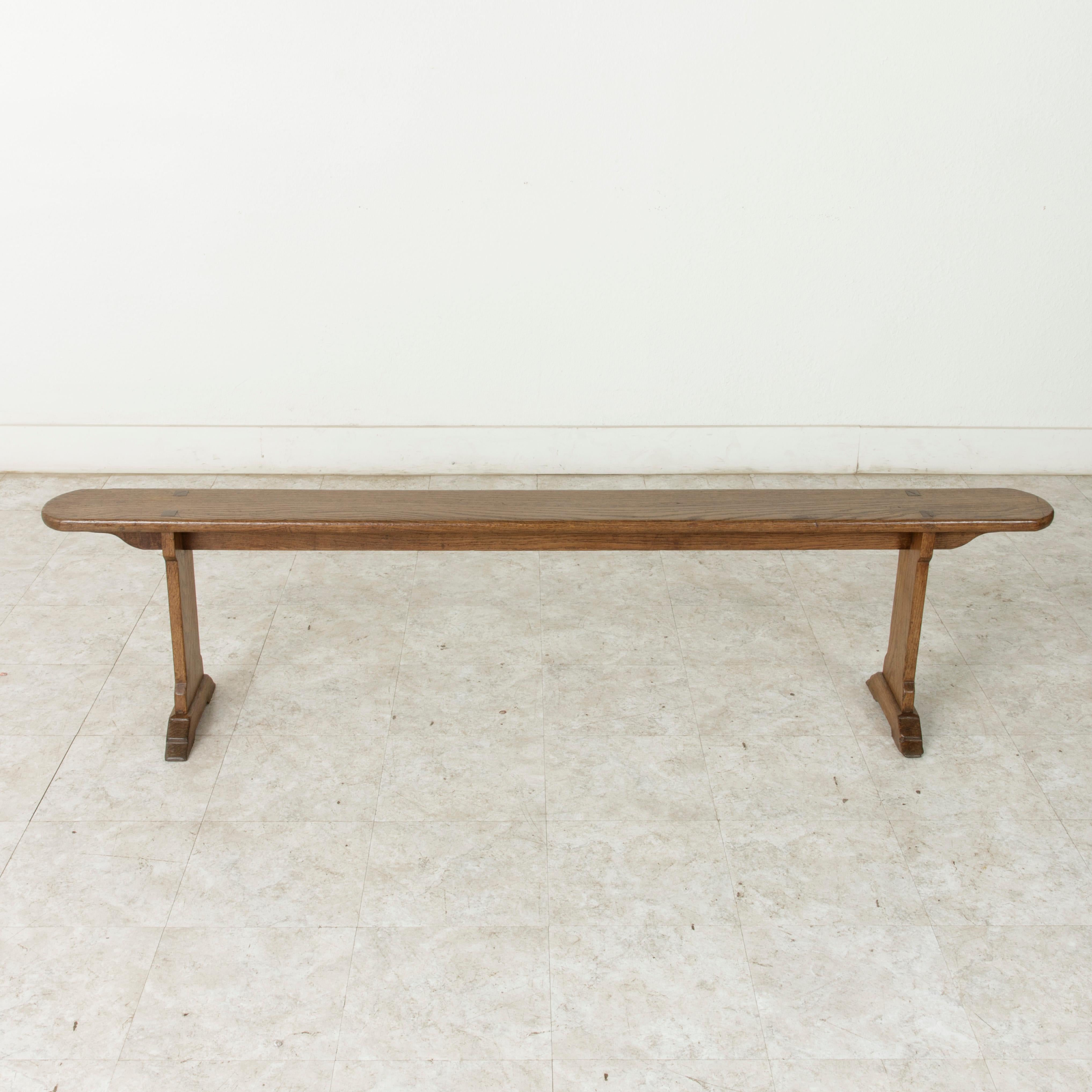 From the region of Normandy, France, this pair of early 20th century artisan-made oak benches measure 75 inches in length. Their seats rest on stretchers that extends their entire length. Seven inch wide seats rest on legs constructed with mortise