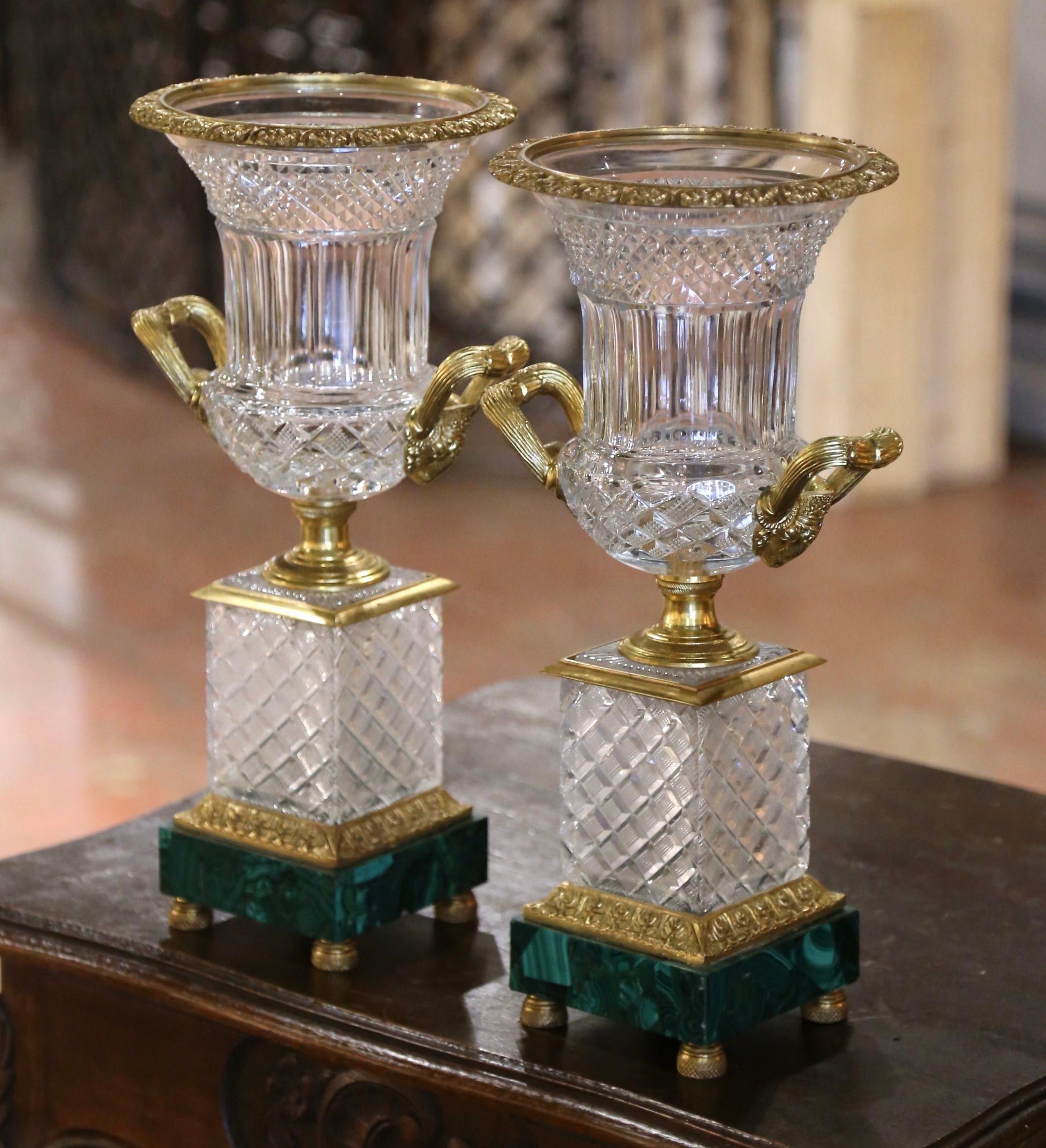 Décorez une cheminée, un buffet ou une console avec ces importants vases anciens. Créée en France vers 1930, chaque urne néoclassique repose sur une base carrée en malachite verte terminée par des pieds chignon en bronze assurant stabilité et