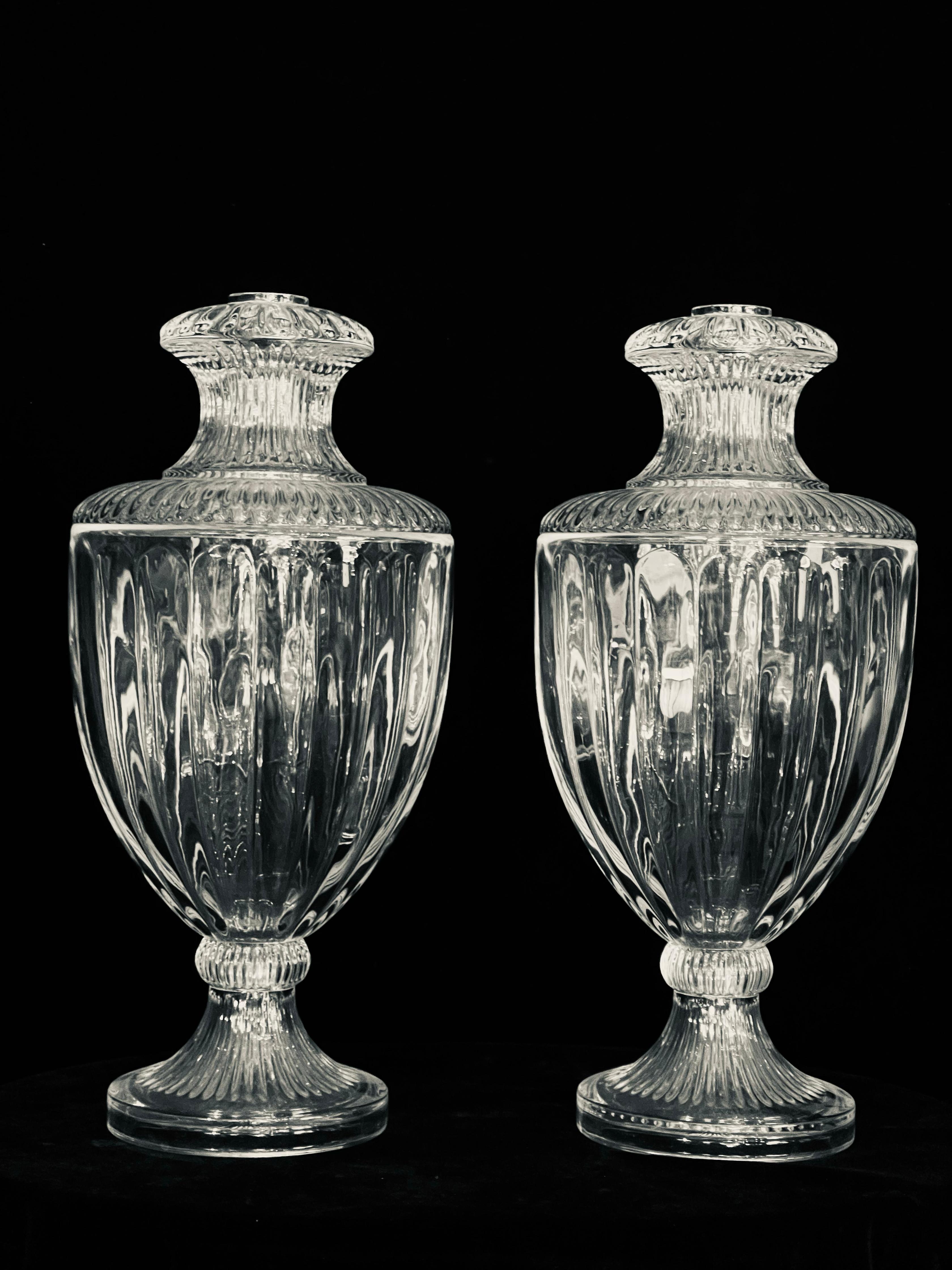 Une paire raffinée et frappante de lampes en cristal de style néoclassique français, attribuées au style de Baccarat et datant probablement du 20e siècle. Chaque lampe présente une gracieuse forme d'urne balustre, fabriquée de manière experte en